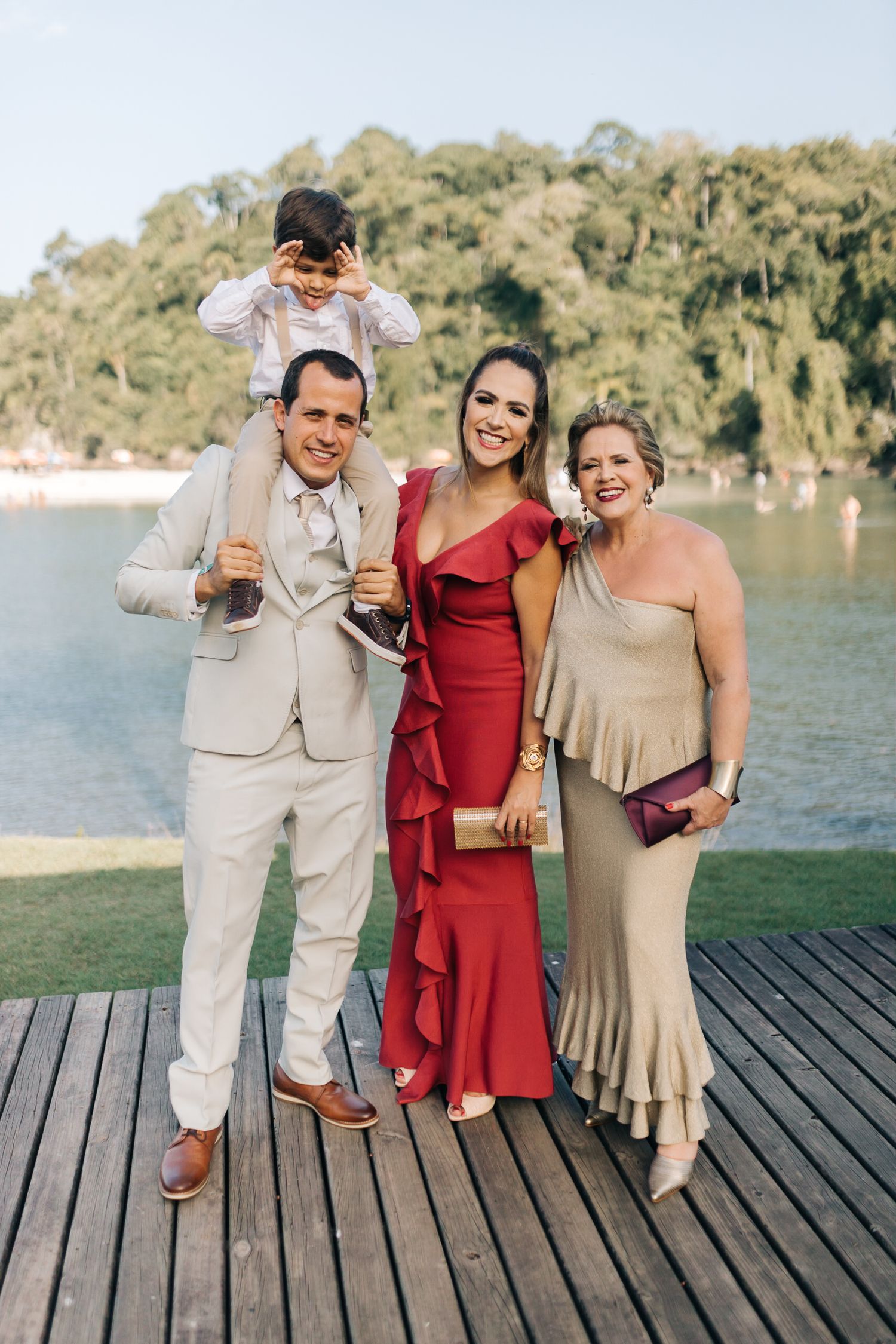 Wedding party posing together on wooden deck by waterfront.