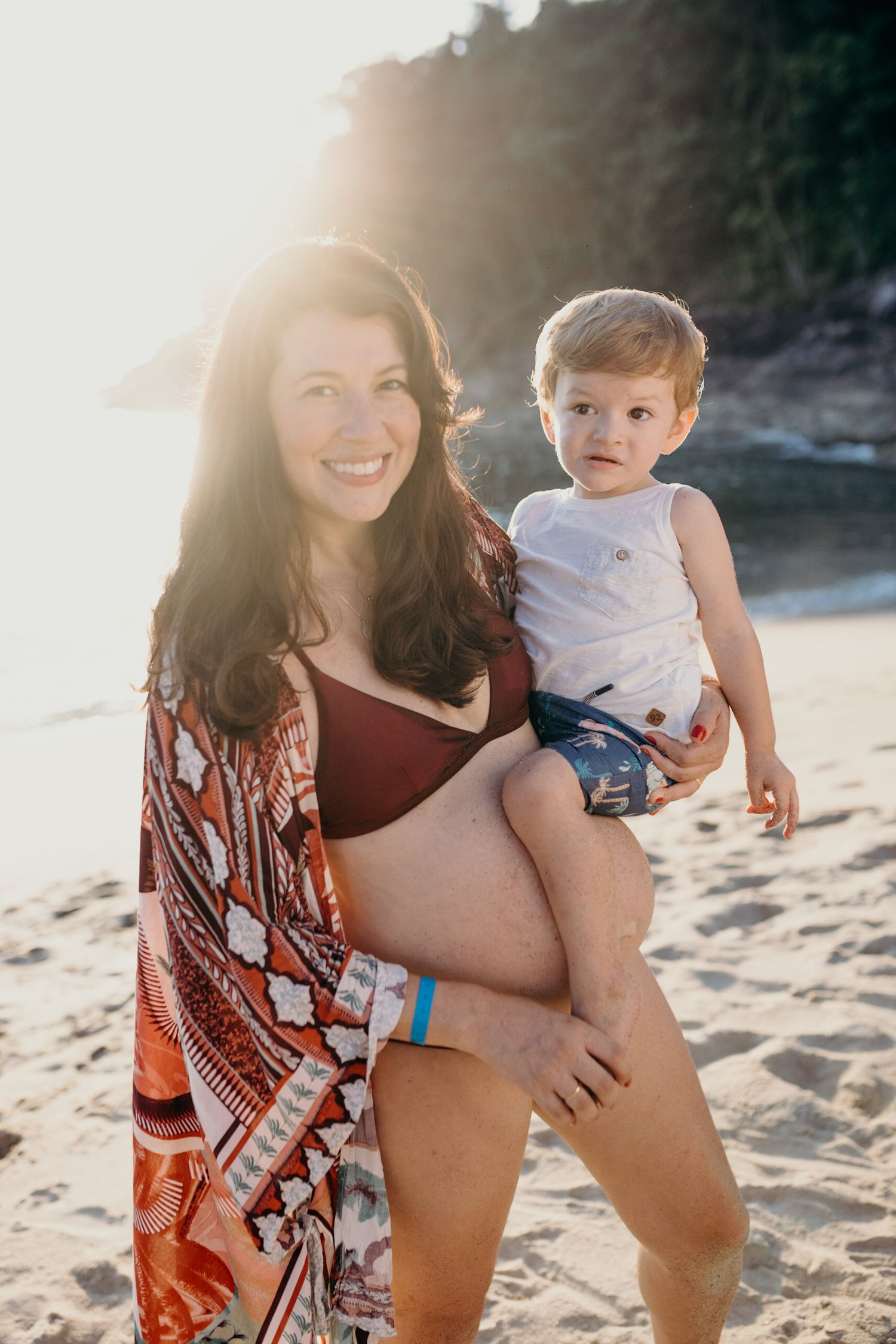 Maternity beach photoshoot featuring family at sunset.