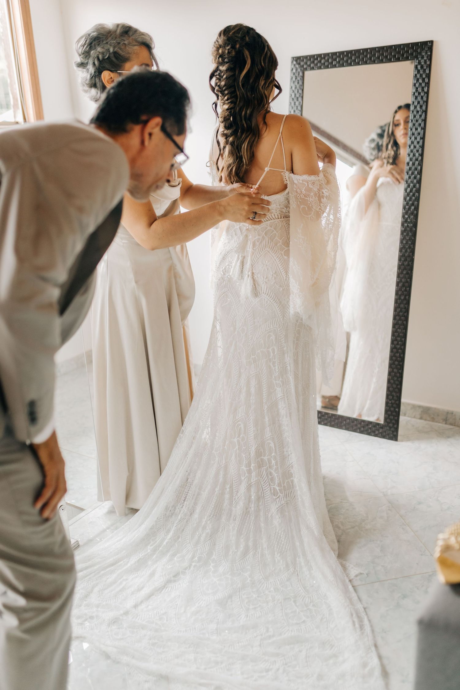 Wedding dress fitting session with reflection in decorative mirror.