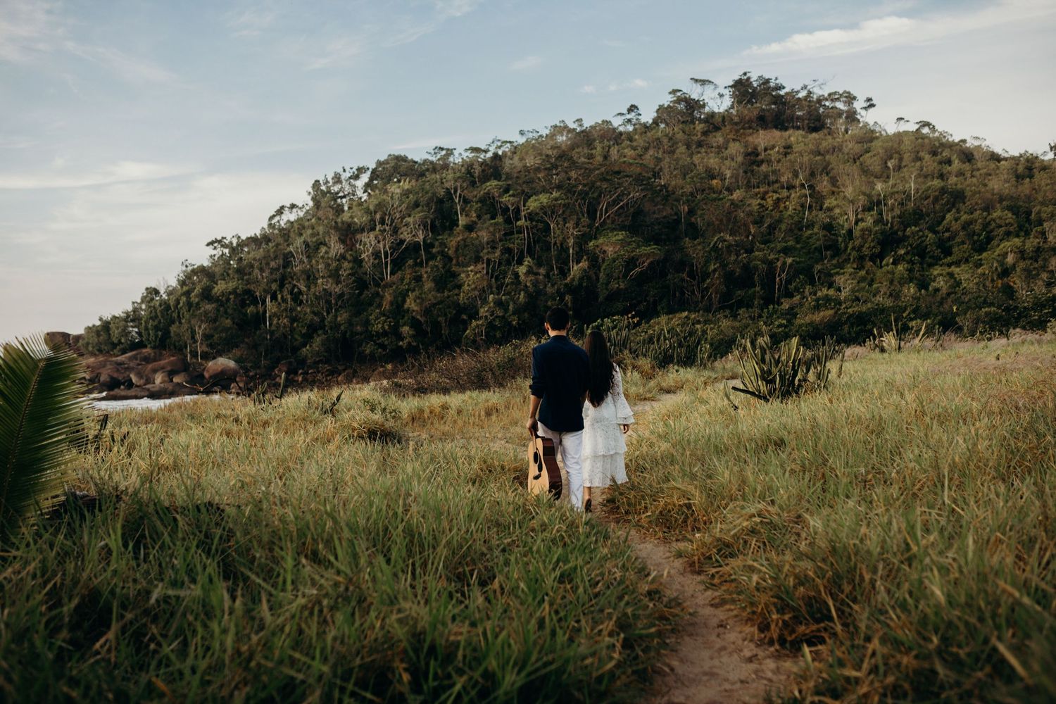 A wide landscape shot of rolling hills and bushland with a couple walking in the distance.