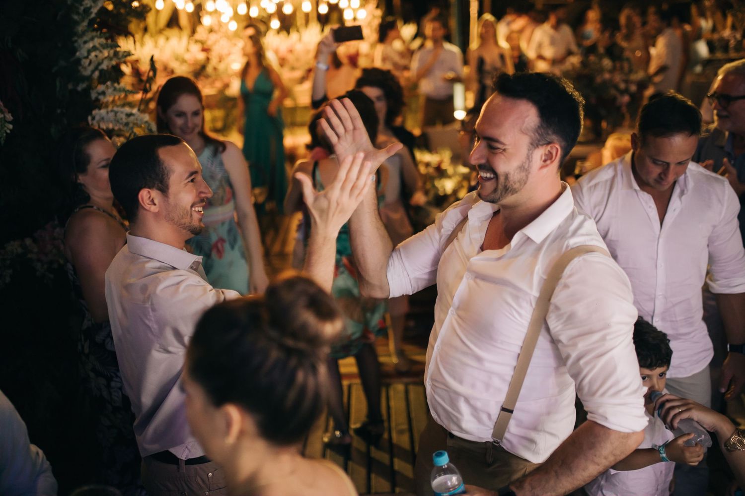 Guests laughing and dancing together during a lively wedding reception celebration.