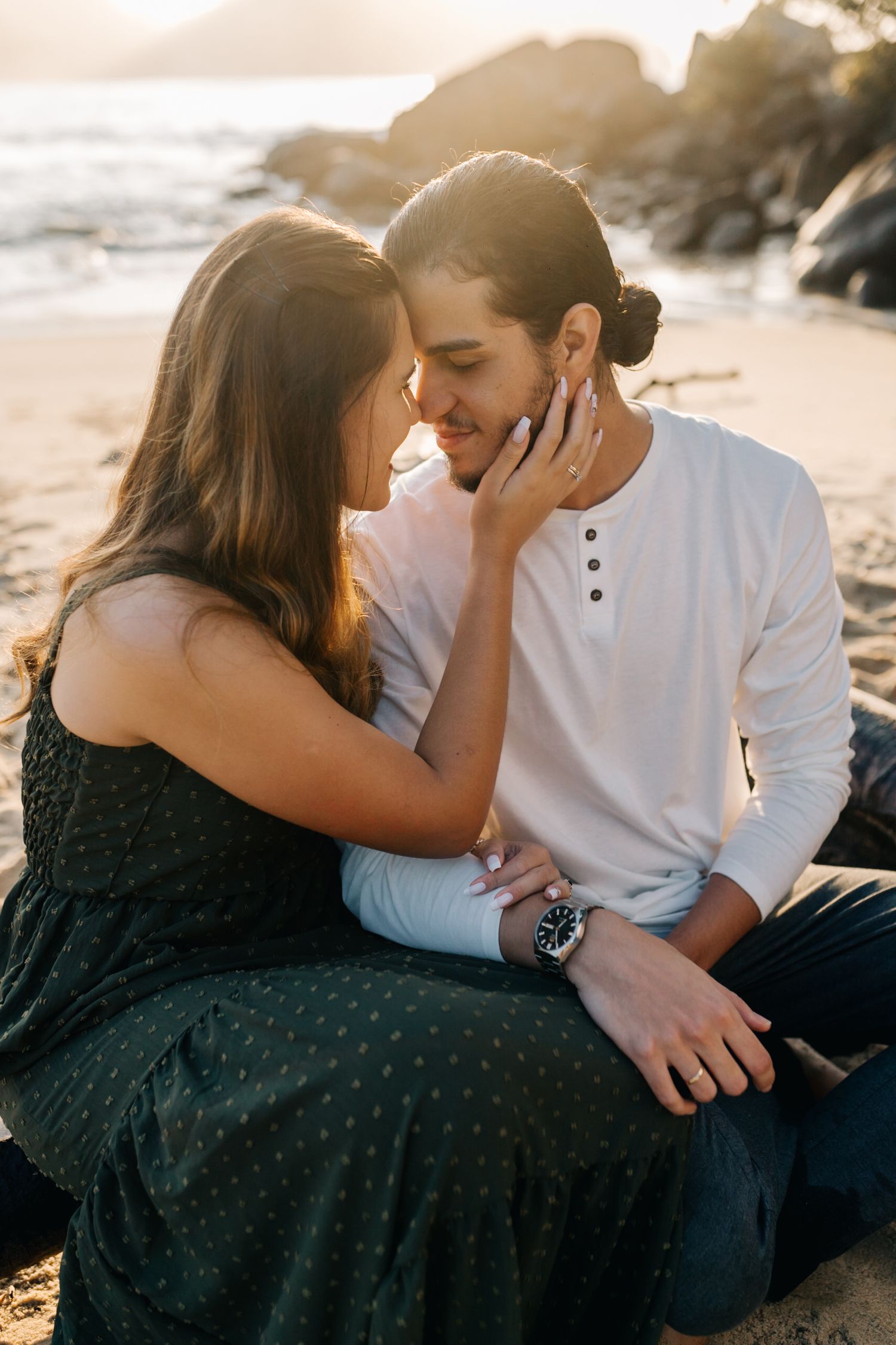 Tender moment between couple during beach engagement photoshoot.
