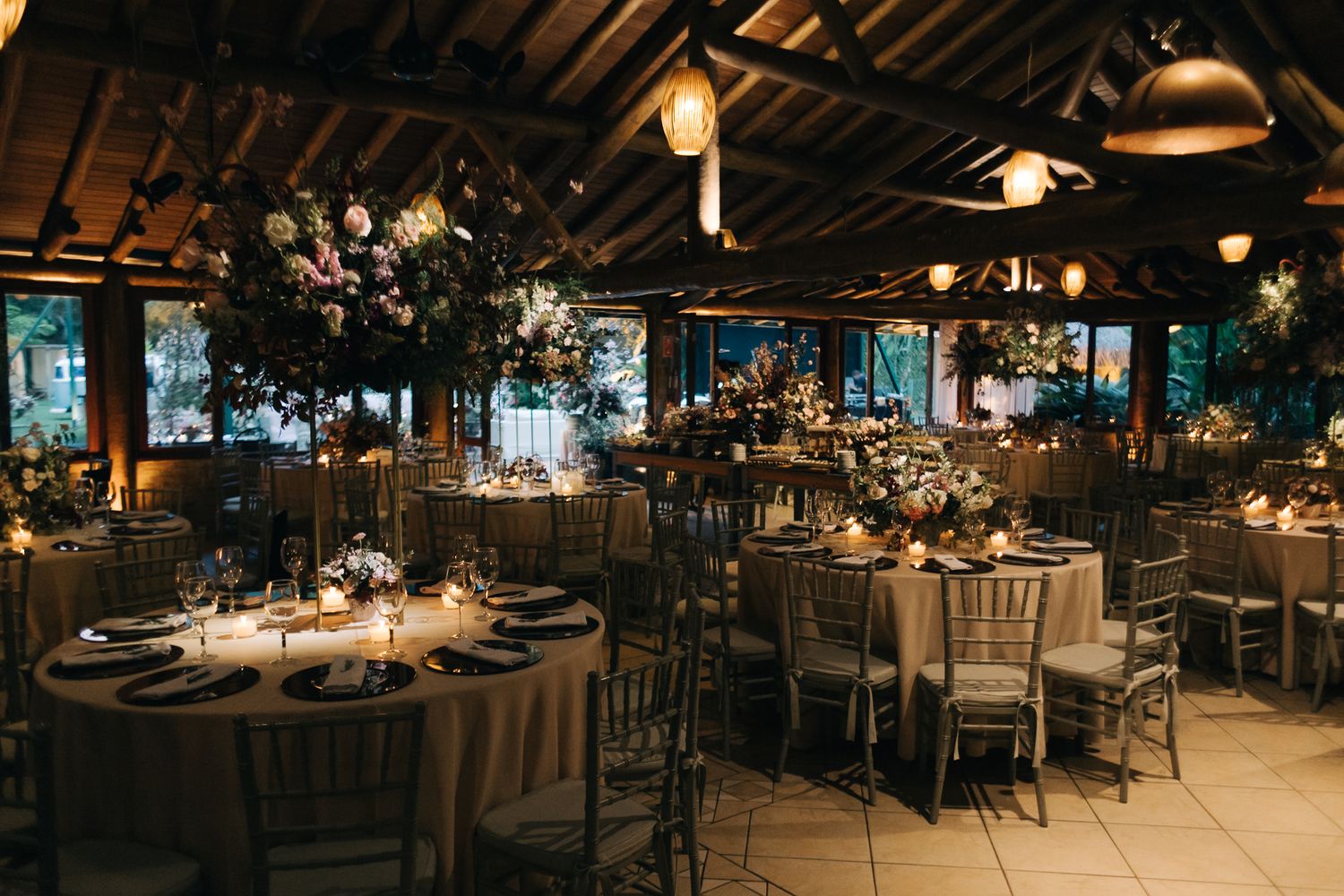 An elegantly decorated reception venue with mood lighting and round tables set for dinner.