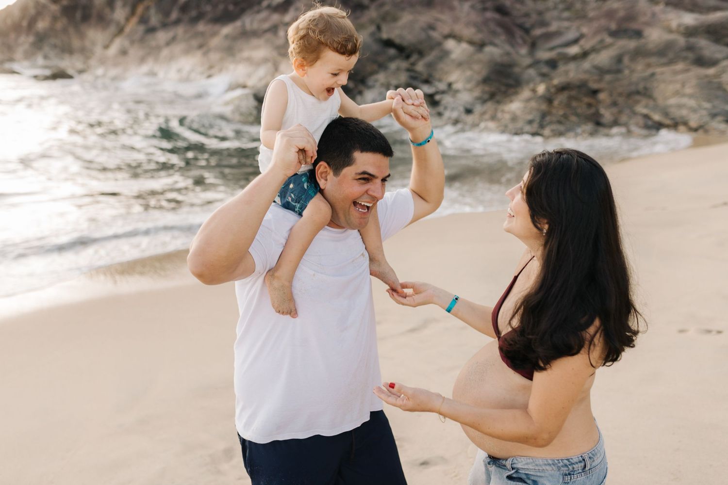 Natural lifestyle family photography session on sandy beach with ocean backdrop.