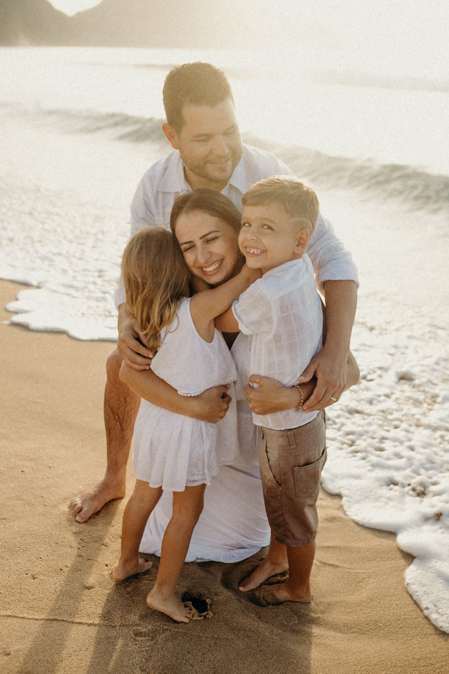 Candid family embrace photographed during golden hour at the beach.