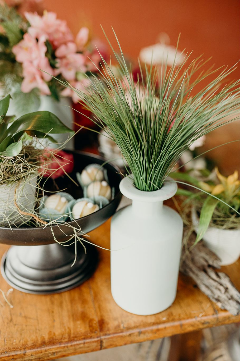 Modern ceramic vases with fresh greenery arranged on wooden surface.