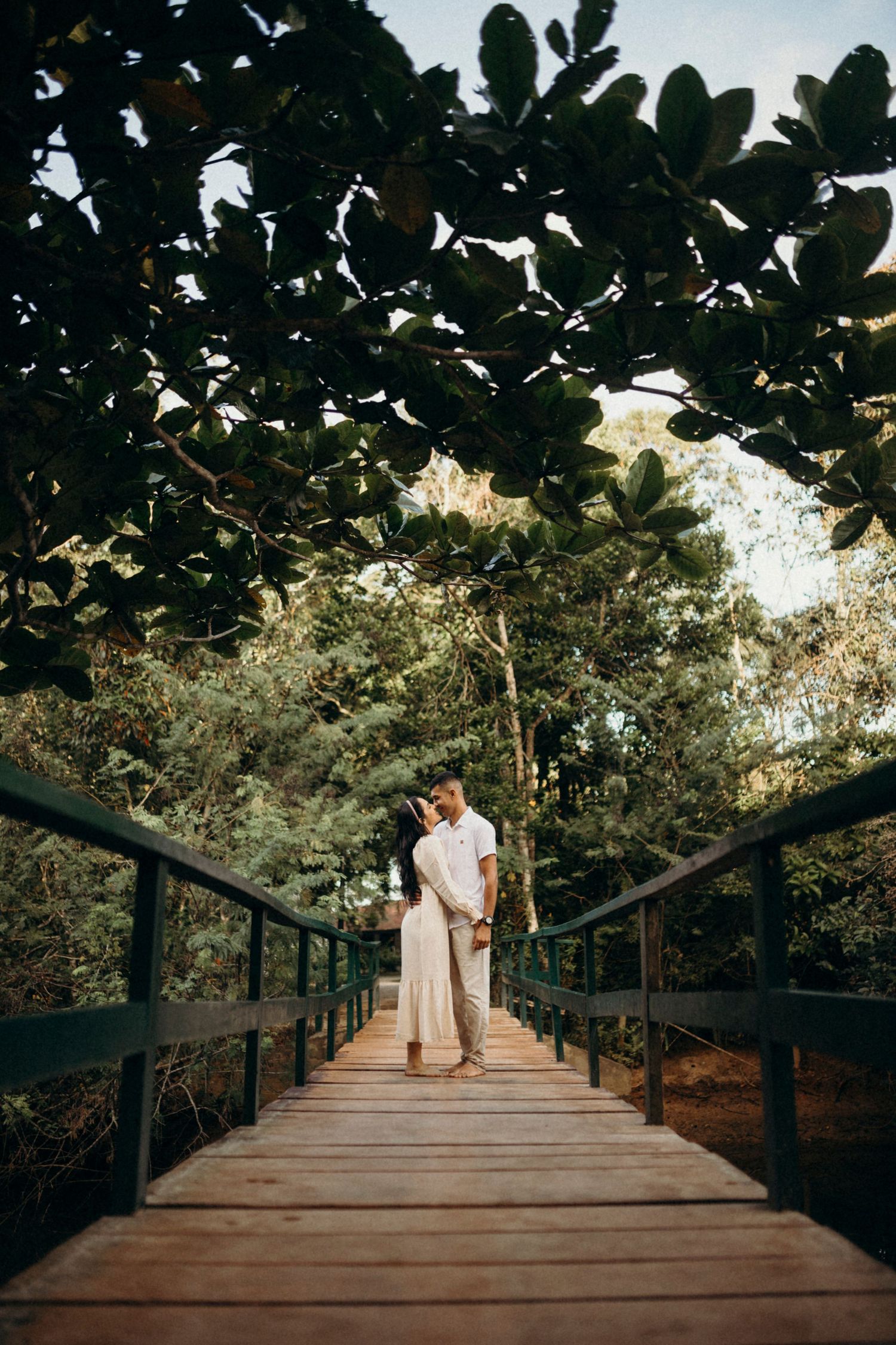 Distant view of couple on wooden boardwalk surrounded by lush foliage.
