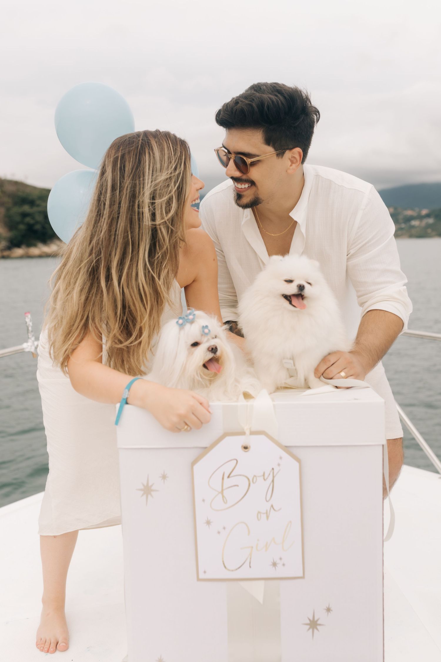 A couple share an intimate moment with their dogs during a boat gender reveal photoshoot.