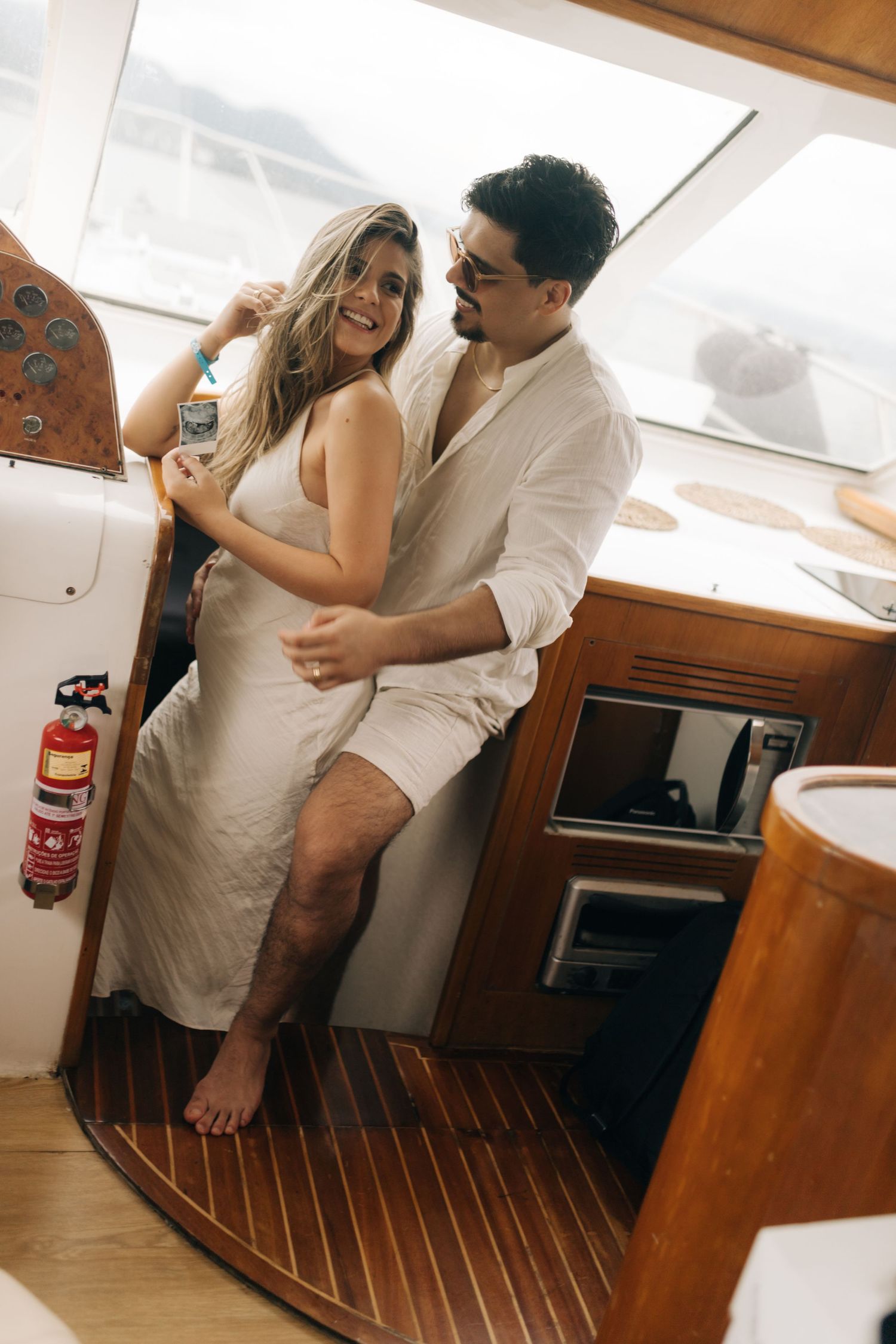 Couple sharing a tender moment in a boat cabin wearing matching white outfits.