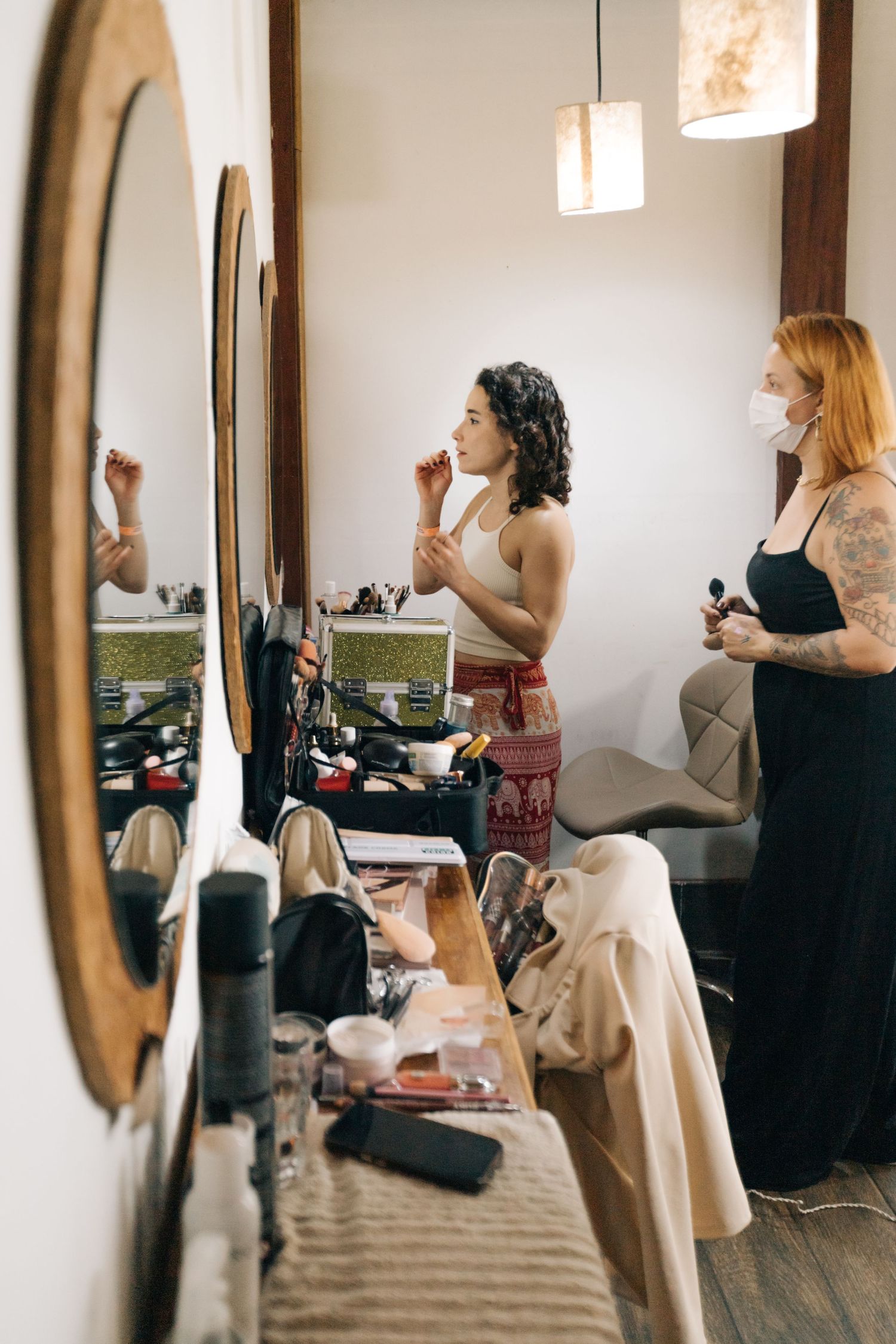 Women applying makeup and getting styled in front of vanity mirrors.