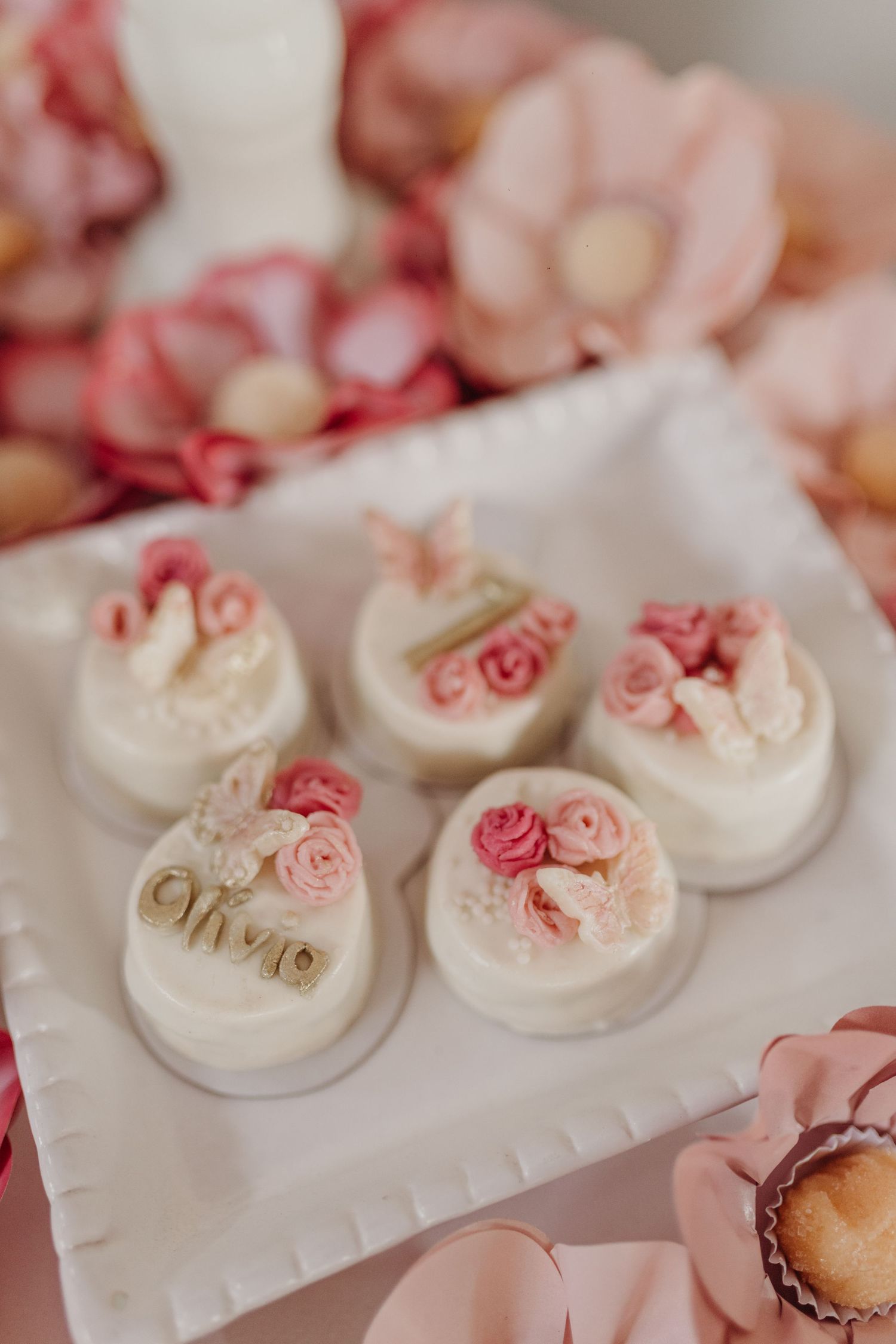 Delicate white desserts decorated with pink floral details arranged on display.