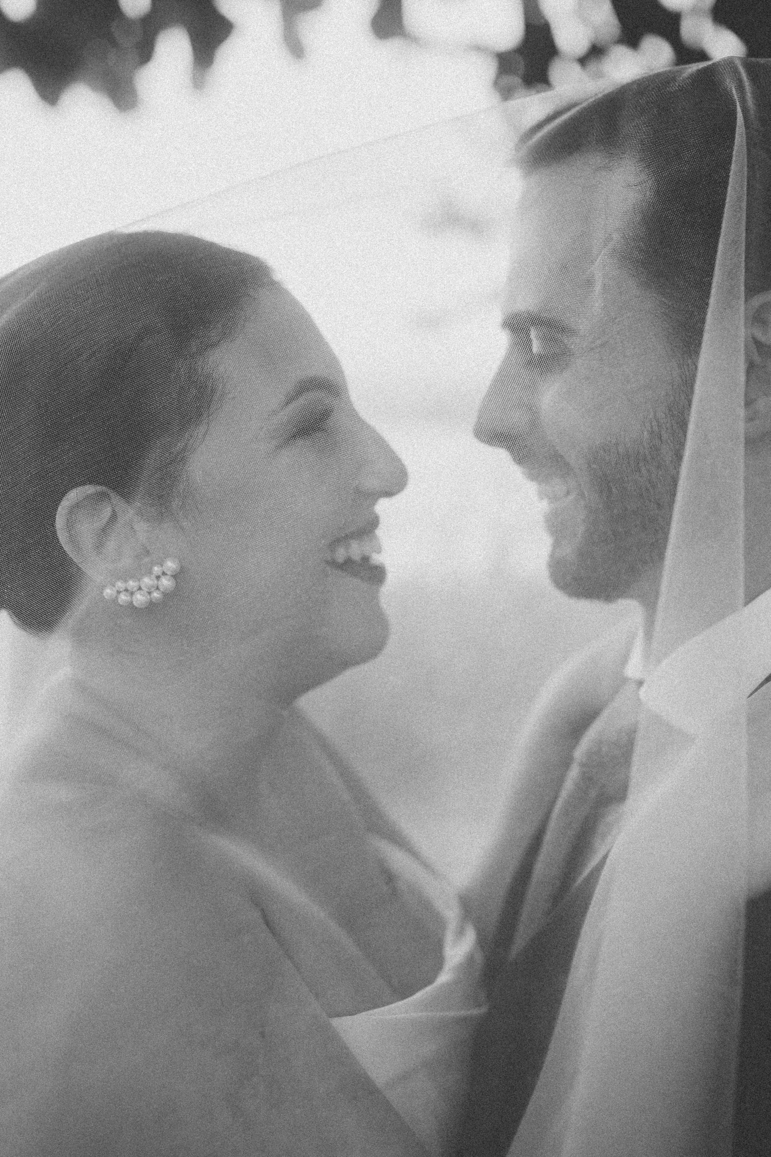 Black and white portrait of a bride and groom sharing an intimate moment under soft lighting.