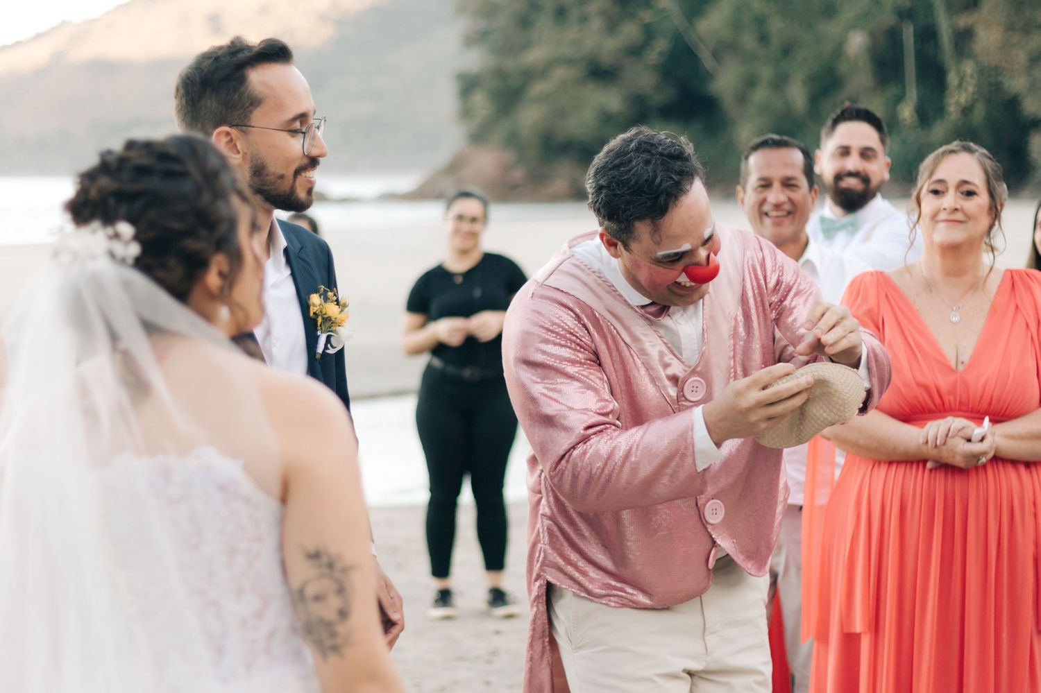 Wedding ceremony guest in pink shirt expresses joyful reaction during outdoor beach celebration.