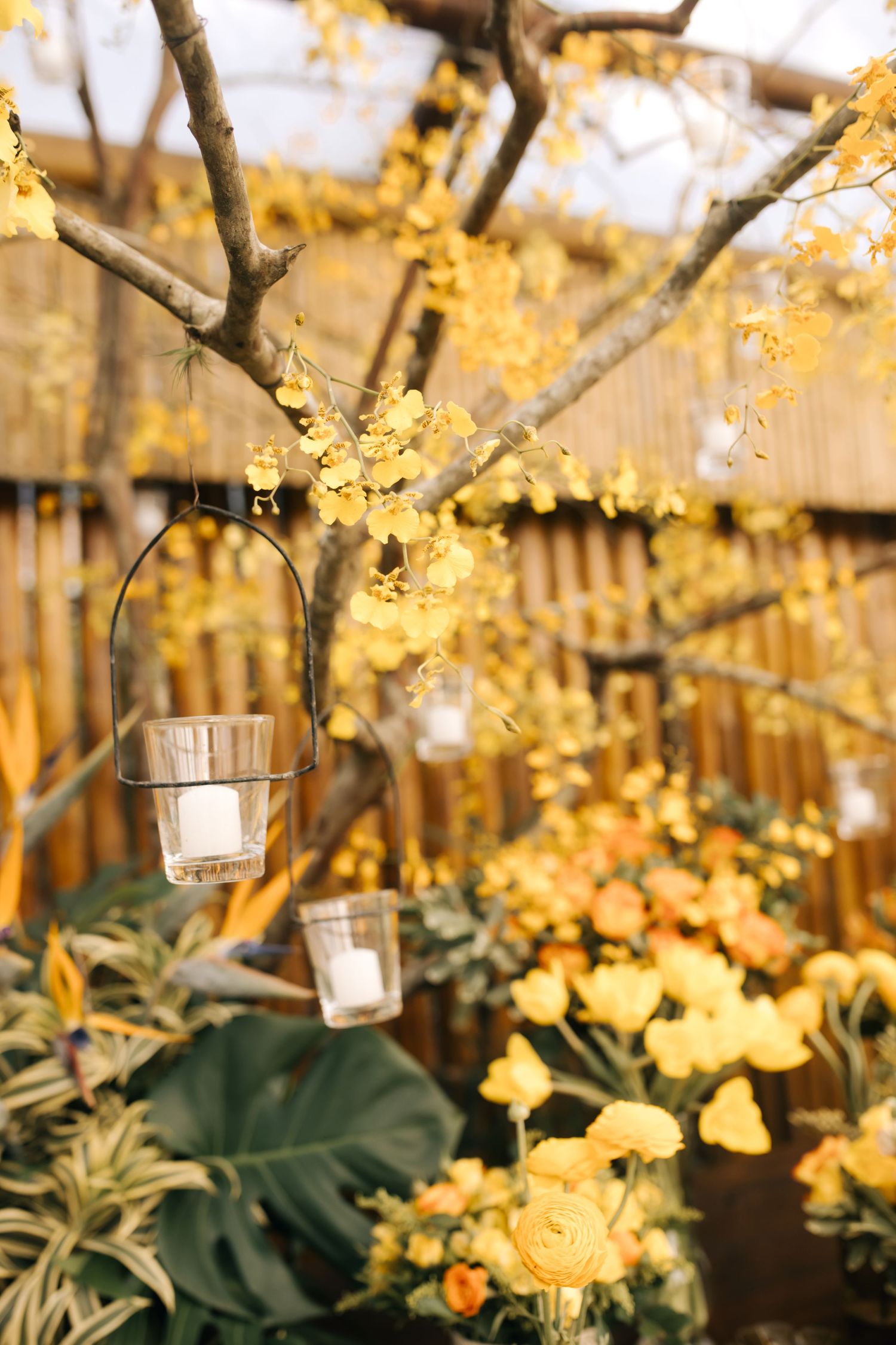 Yellow floral decorations with hanging tea lights creating a romantic outdoor wedding ambiance.