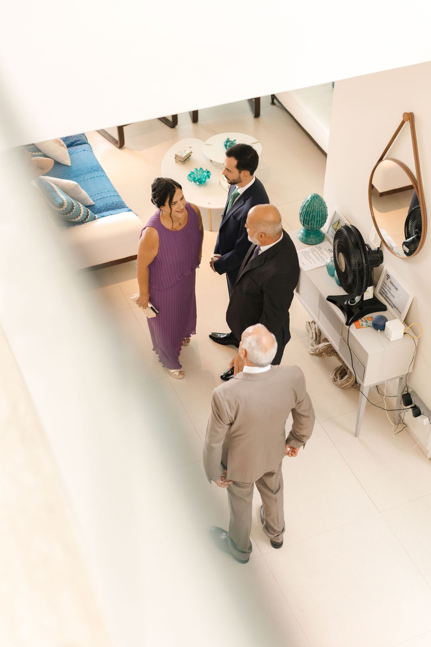 Overhead view of wedding party members gathered in modern white interior space.