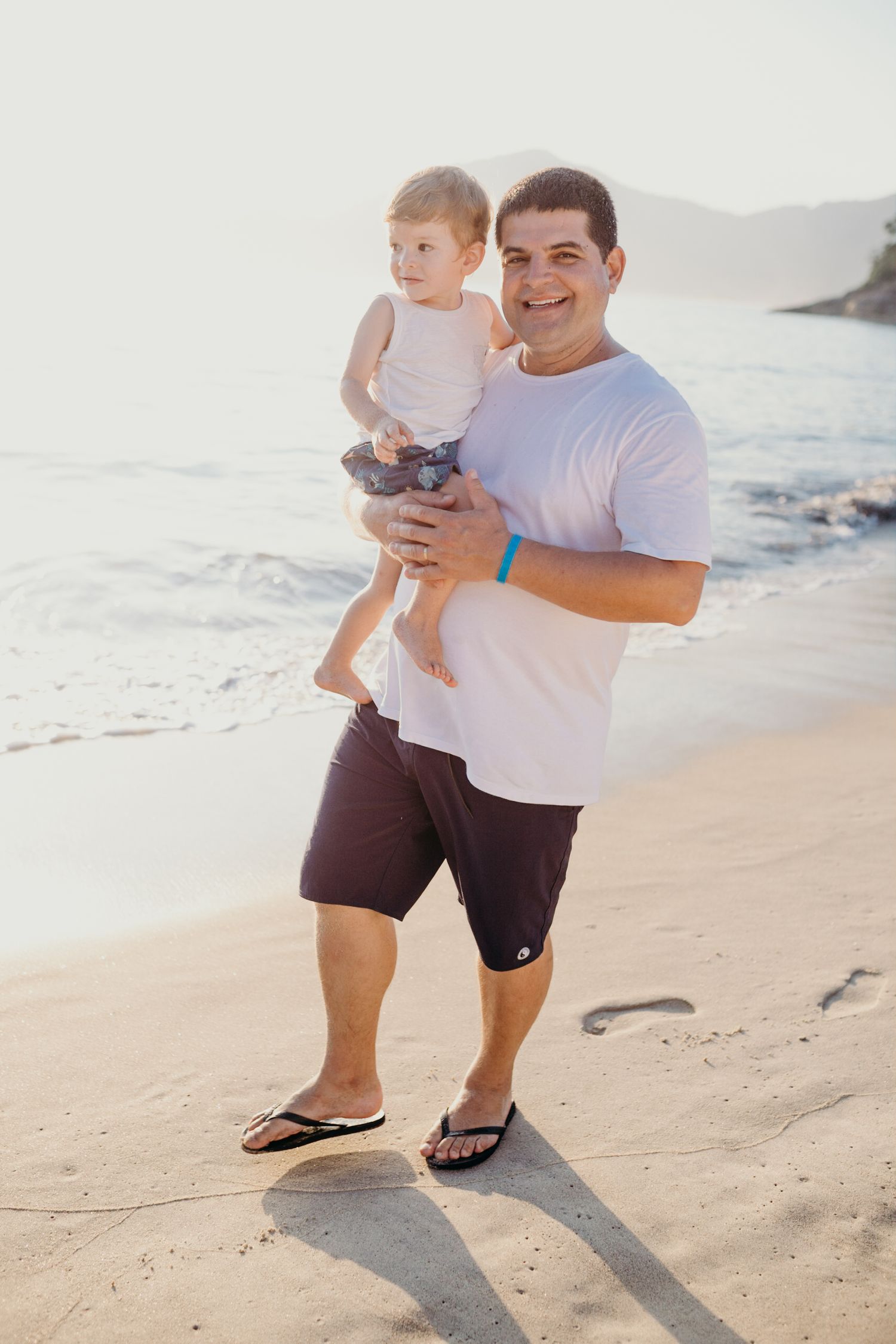 Candid beach portrait with ocean waves and coastal cliffs in background.