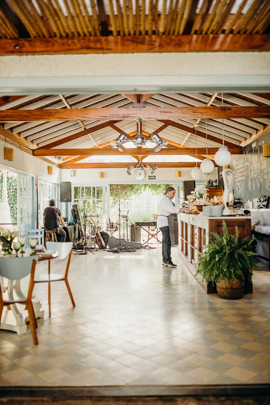 A rustic restaurant interior with wooden beams and natural lighting streaming through large windows.