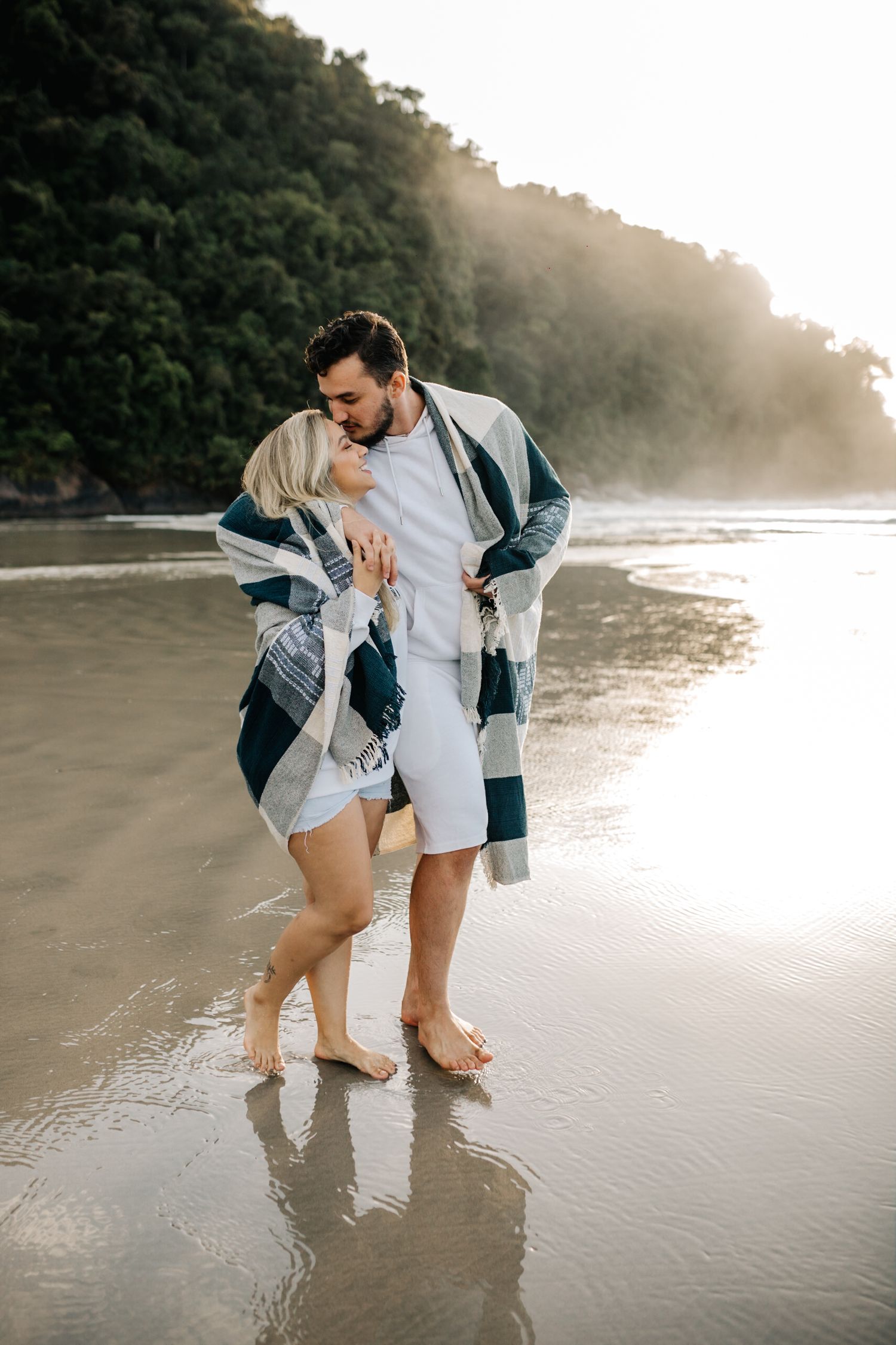 Two people share joyful moments while walking along the beach at sunset.
