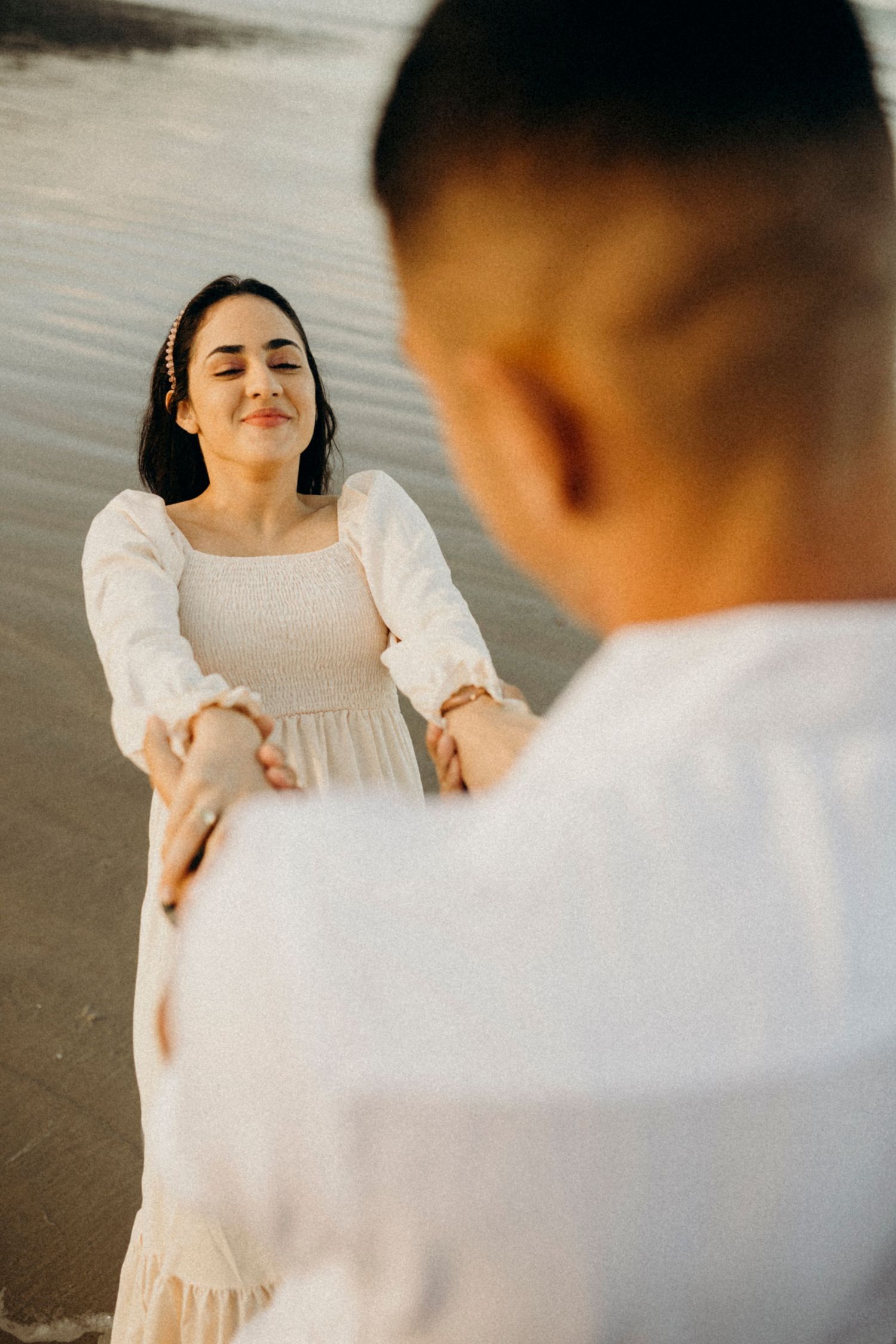 A couple holds hands and shares a joyful moment on the beach.