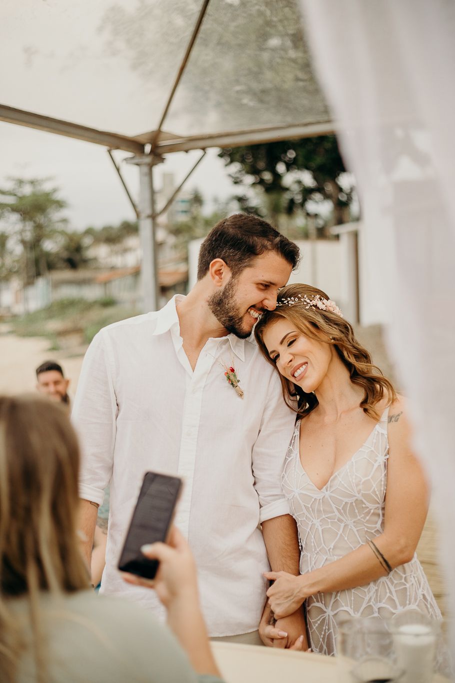 Intimate wedding moment shared between couple under white tent during reception.