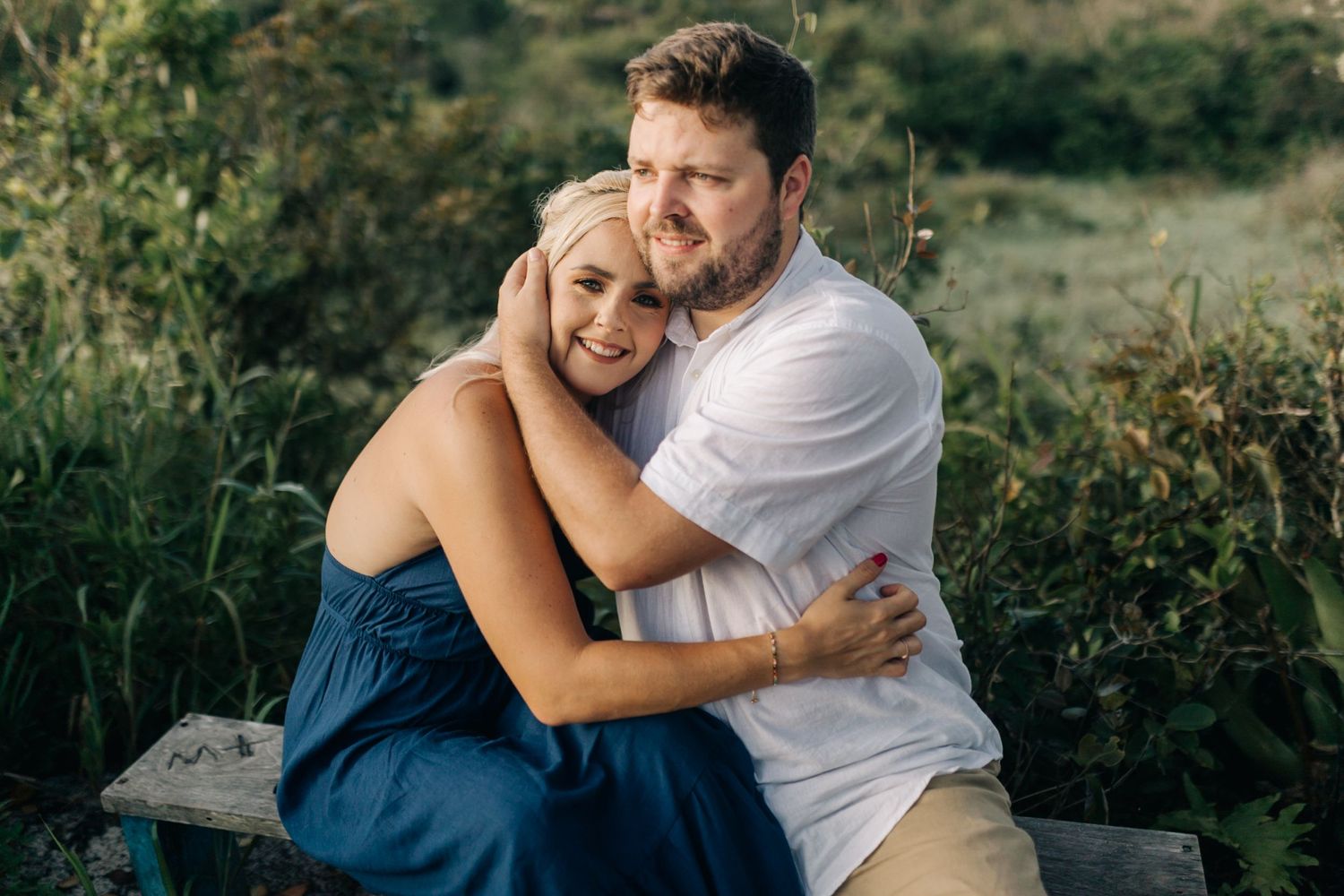 Couple laughing and embracing in outdoor natural setting during golden hour.
