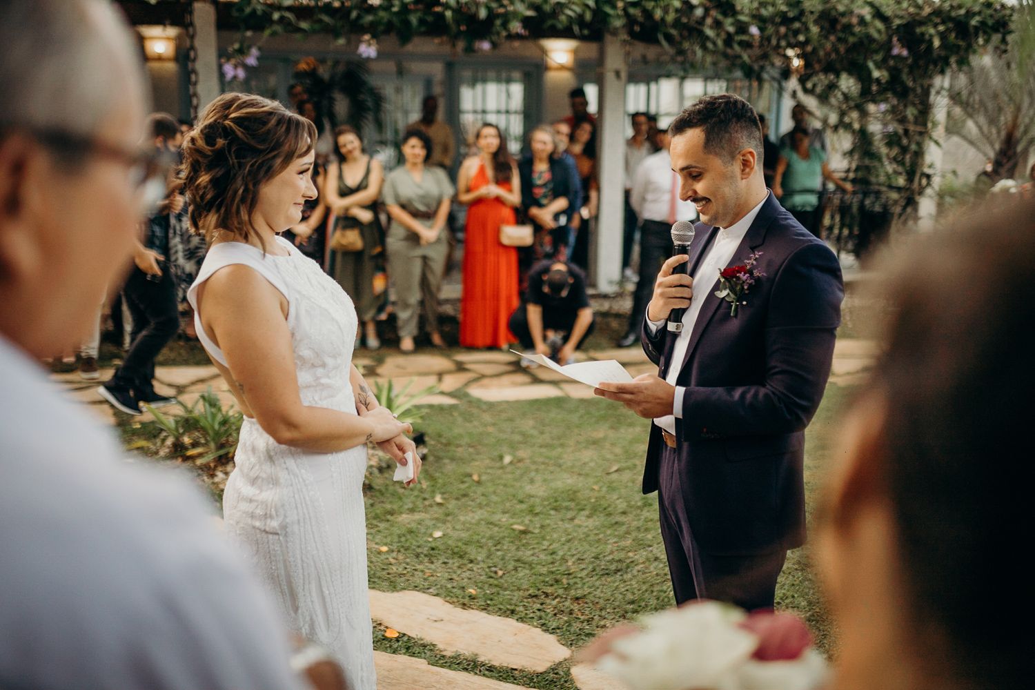 An intimate wedding ceremony moment captured under a pergola with string lights and greenery.