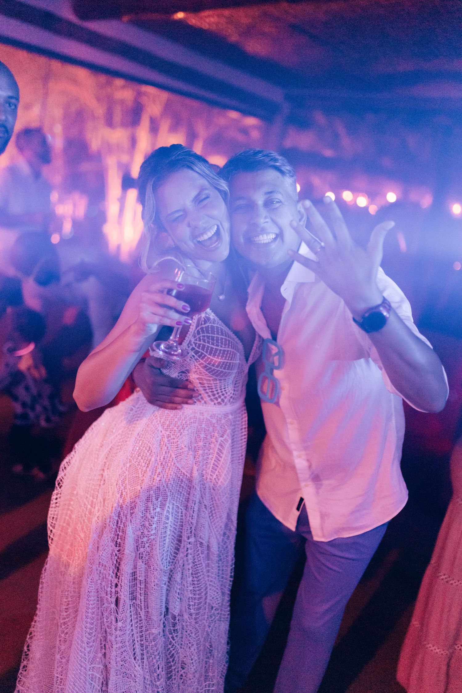 Wedding celebration with guests dancing under purple party lights.