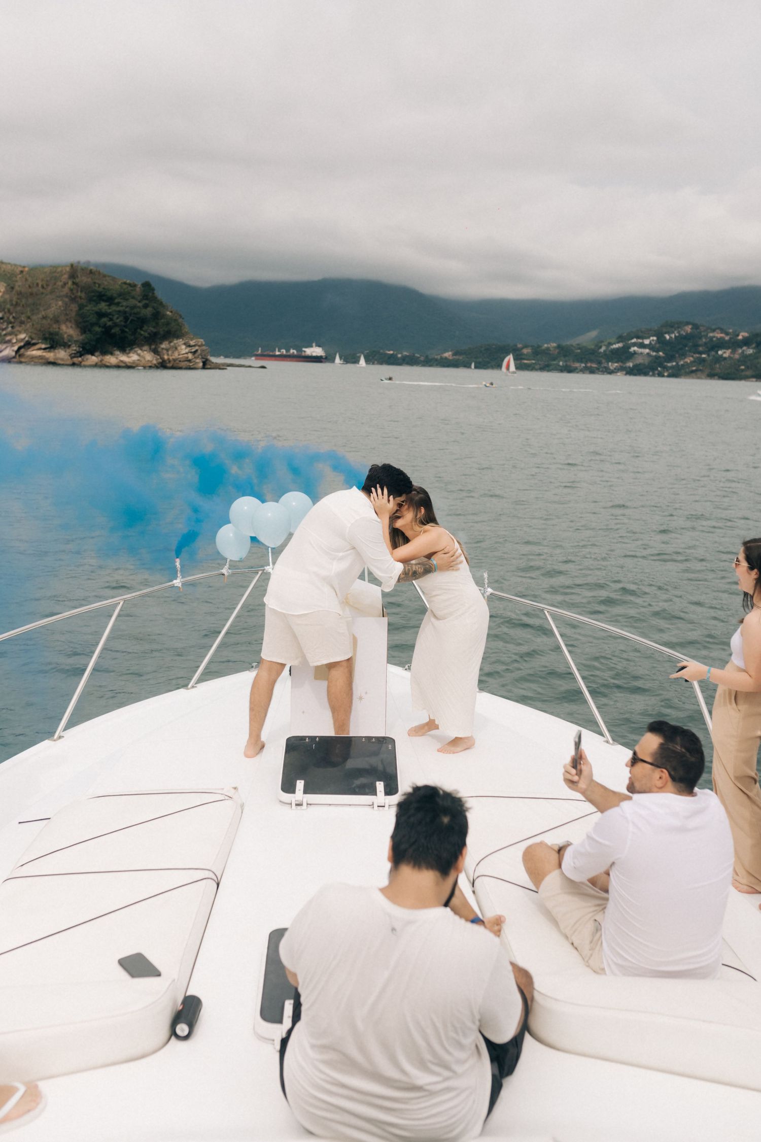 Intimate celebration moment on yacht deck with scenic mountain and harbor views.