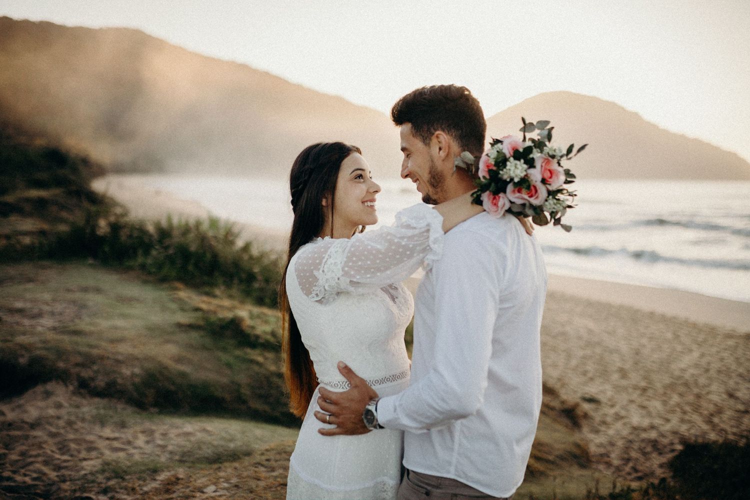 Romantic seaside photoshoot with couple in white attire.