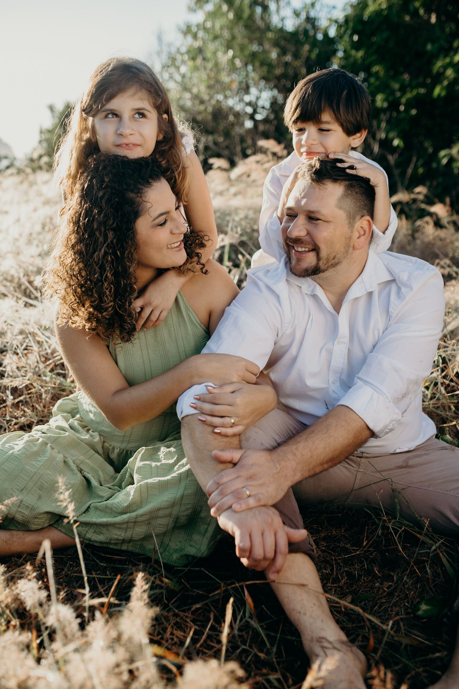 A couple enjoys a tender moment together while sitting in a sunny outdoor setting.