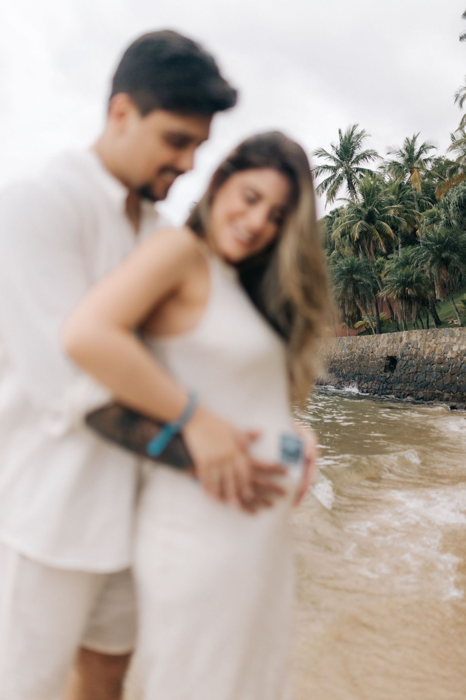 A dreamy beach photoshoot with palm trees and soft focus in the foreground.