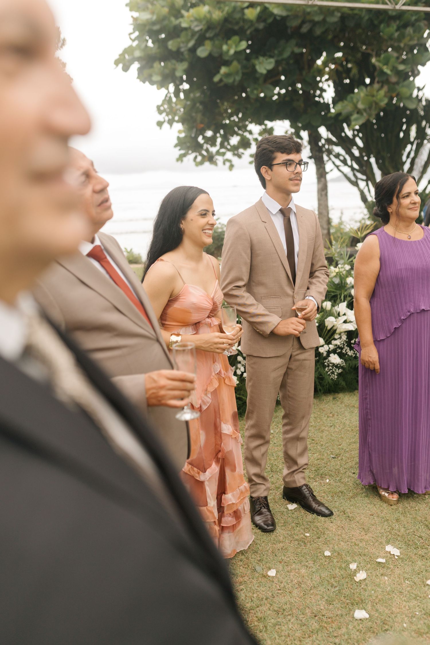 Wedding guests in formal attire gathered outdoors for celebration.