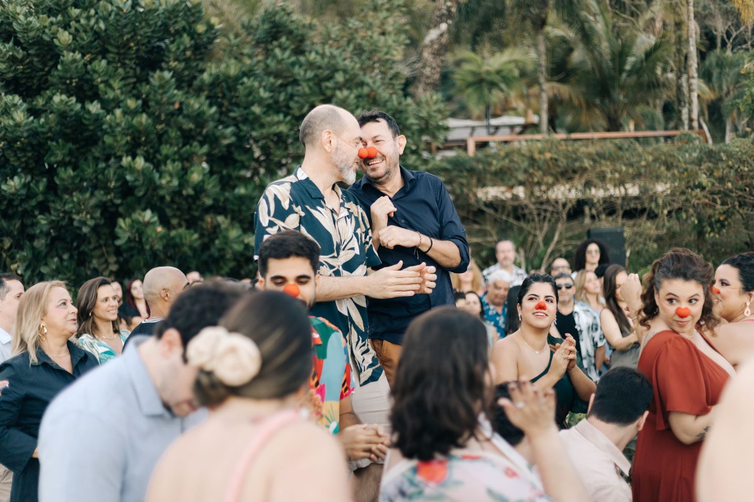 Wedding reception guests dance and celebrate outdoors under natural lighting.
