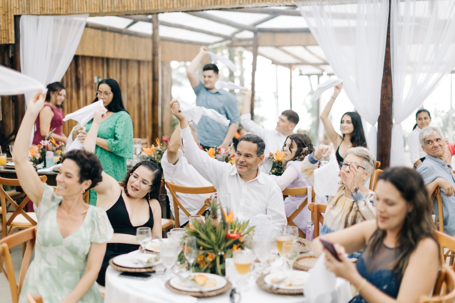 Energetic wedding guests raise their arms in celebration during reception.