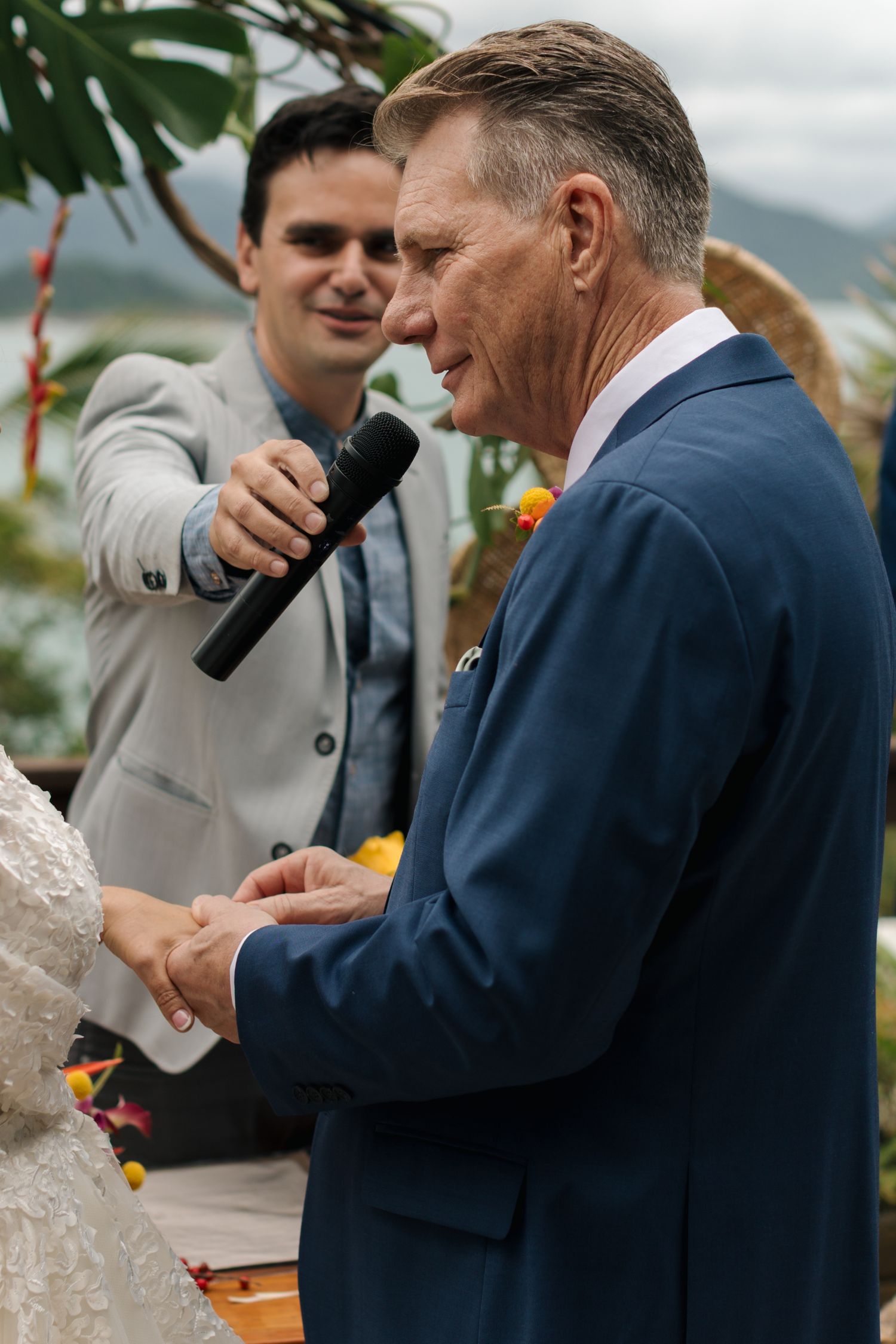Wedding ceremony moments captured outdoors with tropical decor and mountains in view.