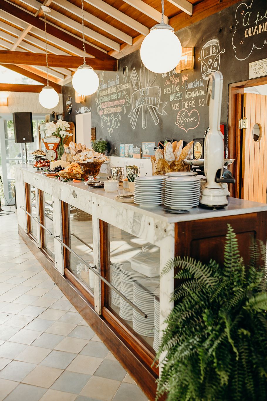 Modern restaurant buffet station with chalkboard menu, glass displays, and pendant lighting.