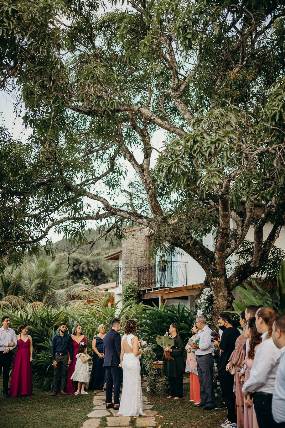 Wedding guests gather under eucalyptus trees during an outdoor ceremony.