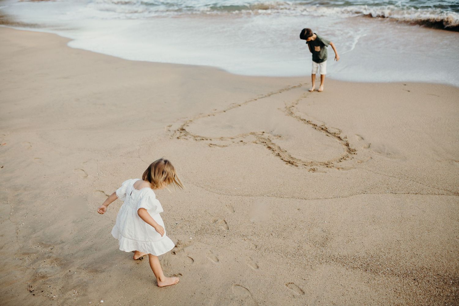 A small figure runs along the sandy beach near the ocean.