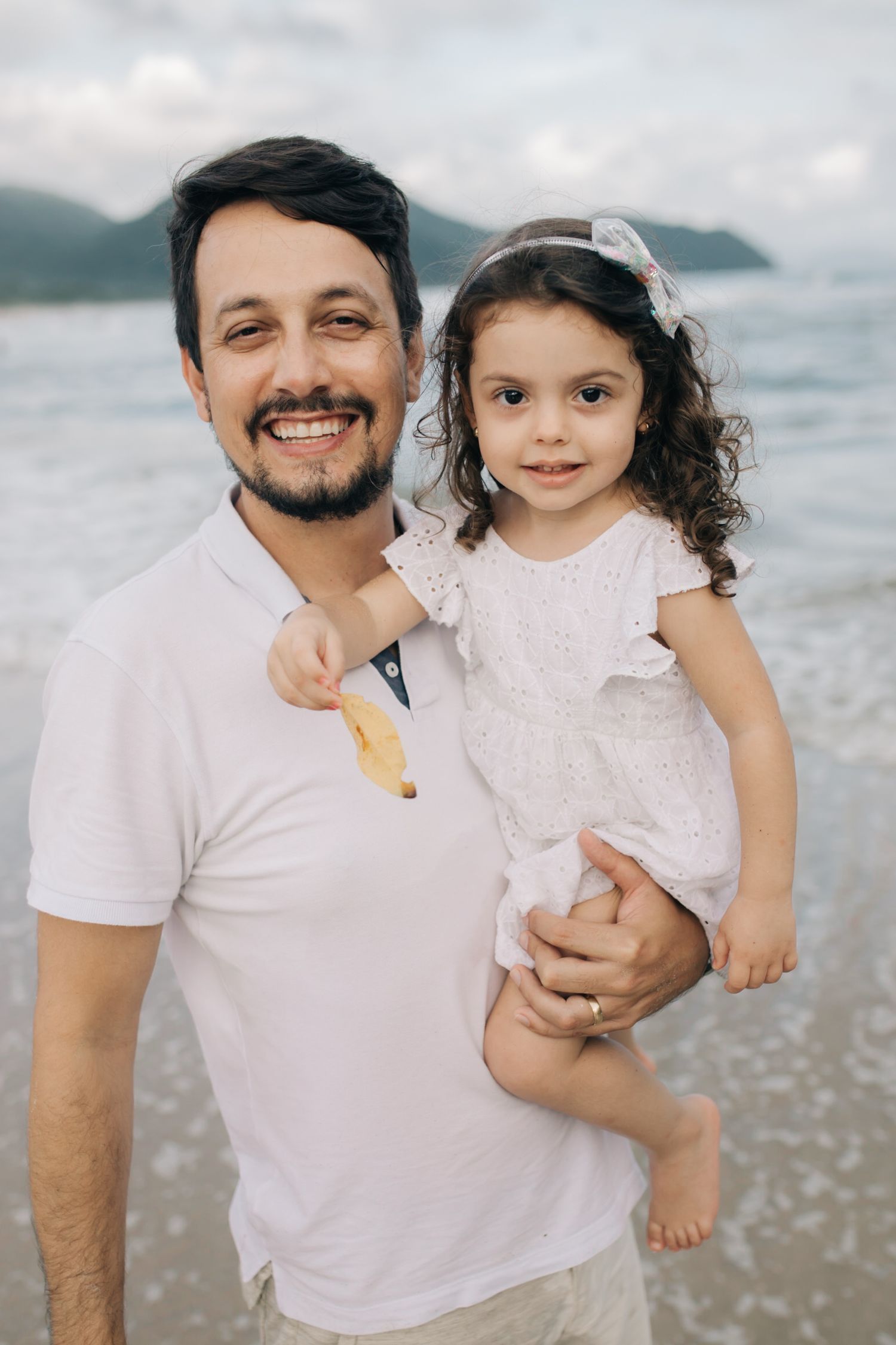A heartwarming beach photoshoot shows a family enjoying time together by the ocean.