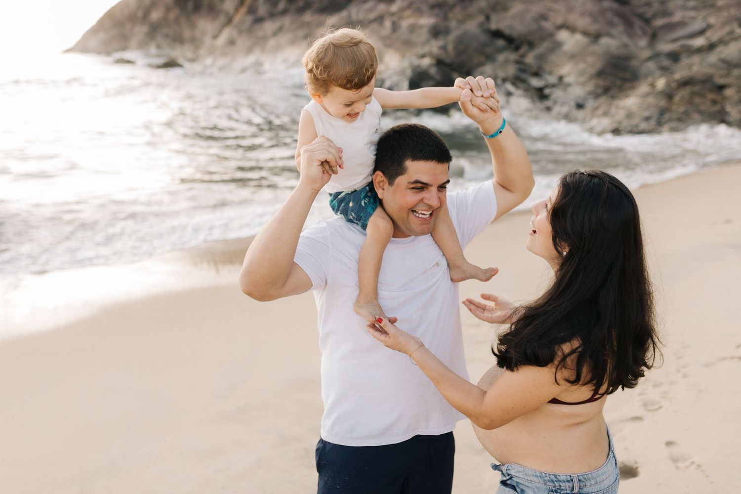 Candid family moment captured during beach photoshoot with waves in background.