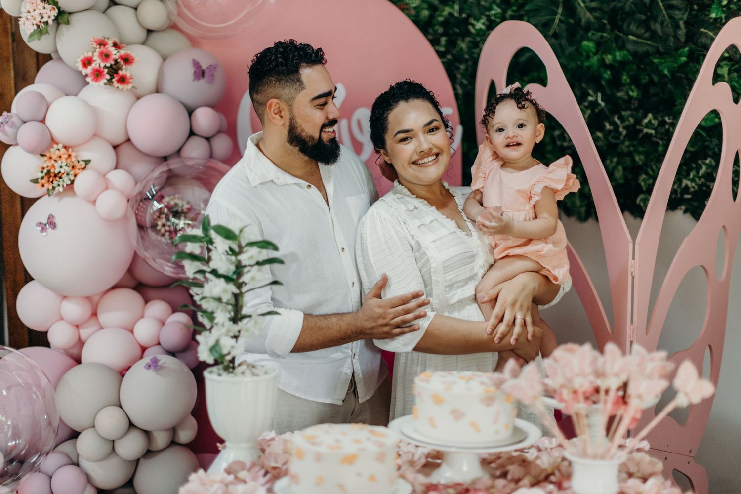 Festive pink and white balloon arch decorates an outdoor celebration setting.