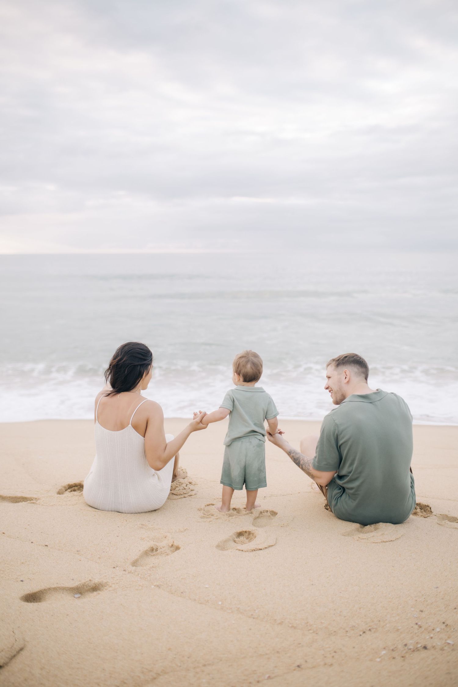 Three people relax on a peaceful beach while enjoying the ocean view together.