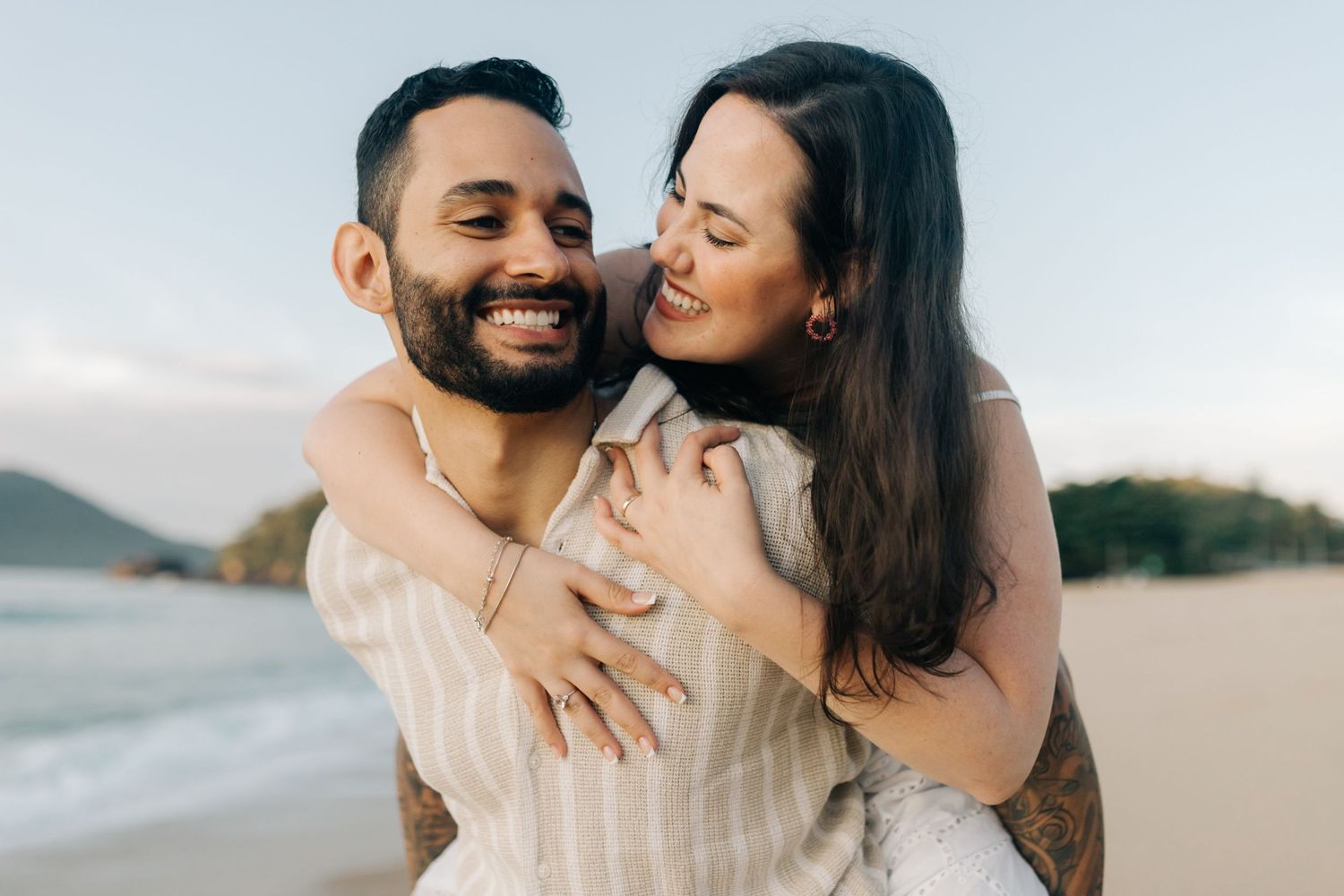Happy couple sharing a playful moment on the beach during golden hour.