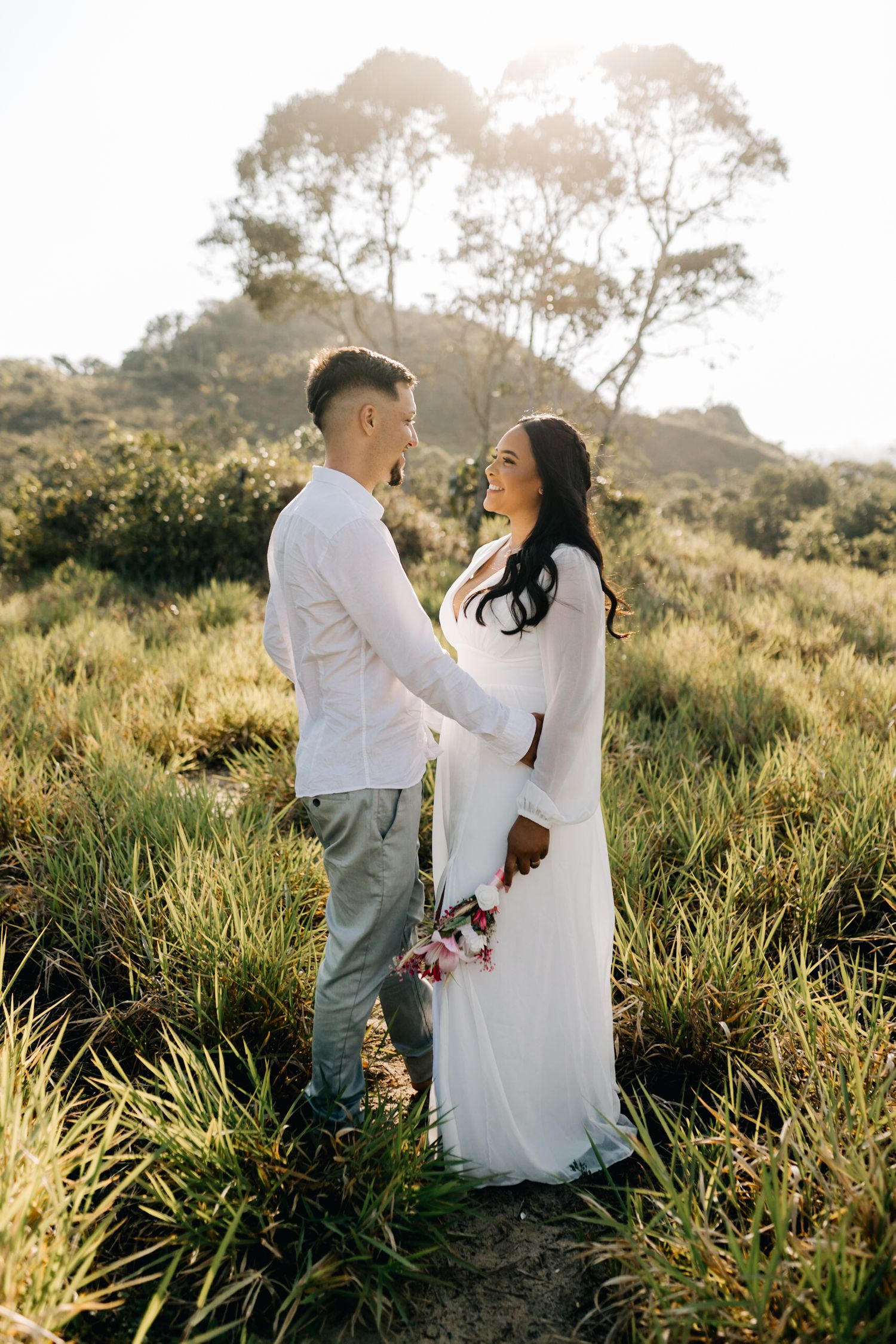 Couple sharing intimate moments among tall grass during a golden hour photoshoot.