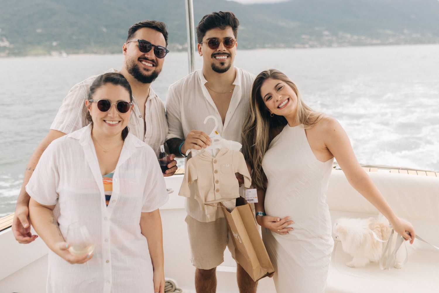 A joyful group celebrates on a sunny beach wearing coordinated white and beige outfits.