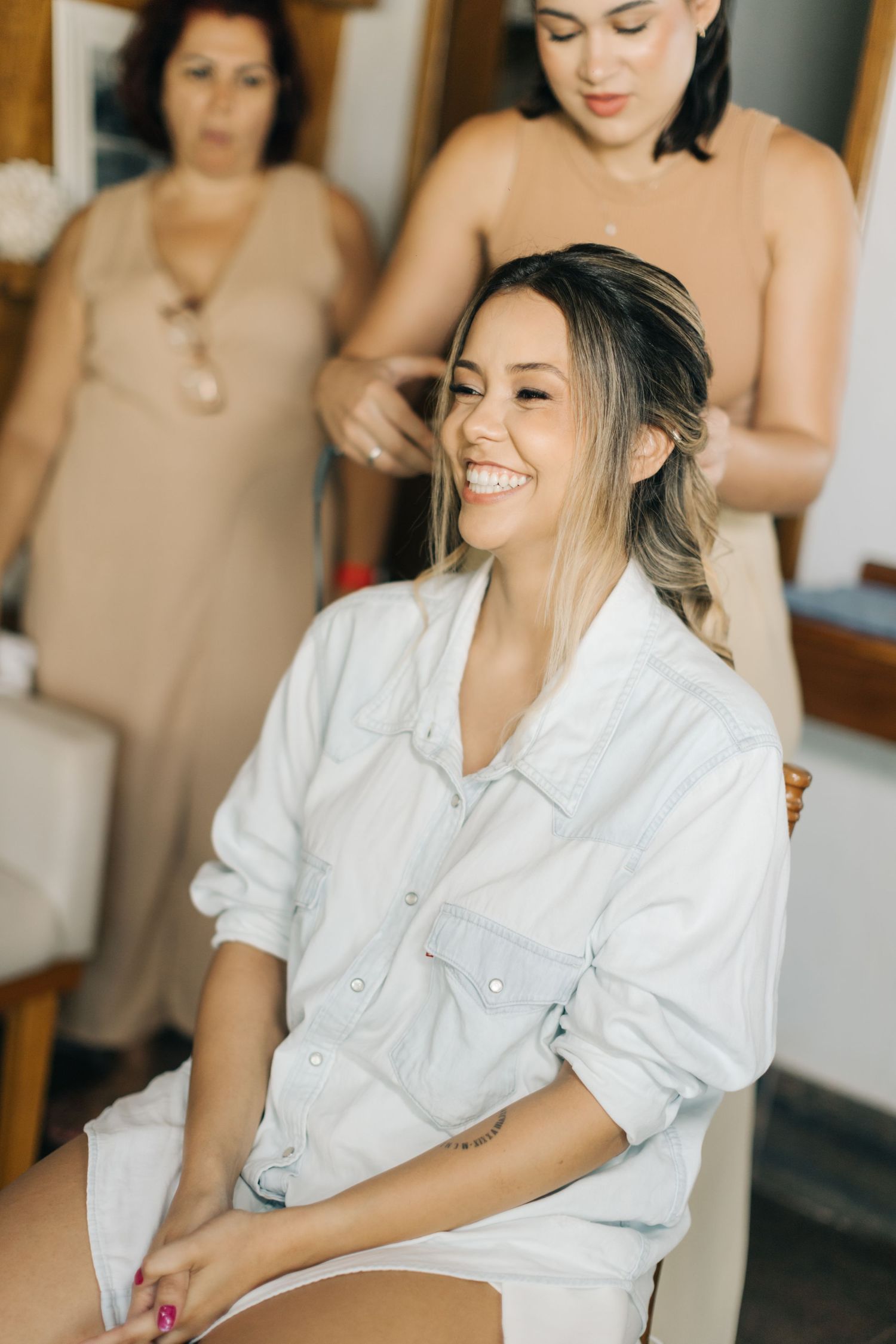Person in white button-down shirt getting hair styled in preparation room.