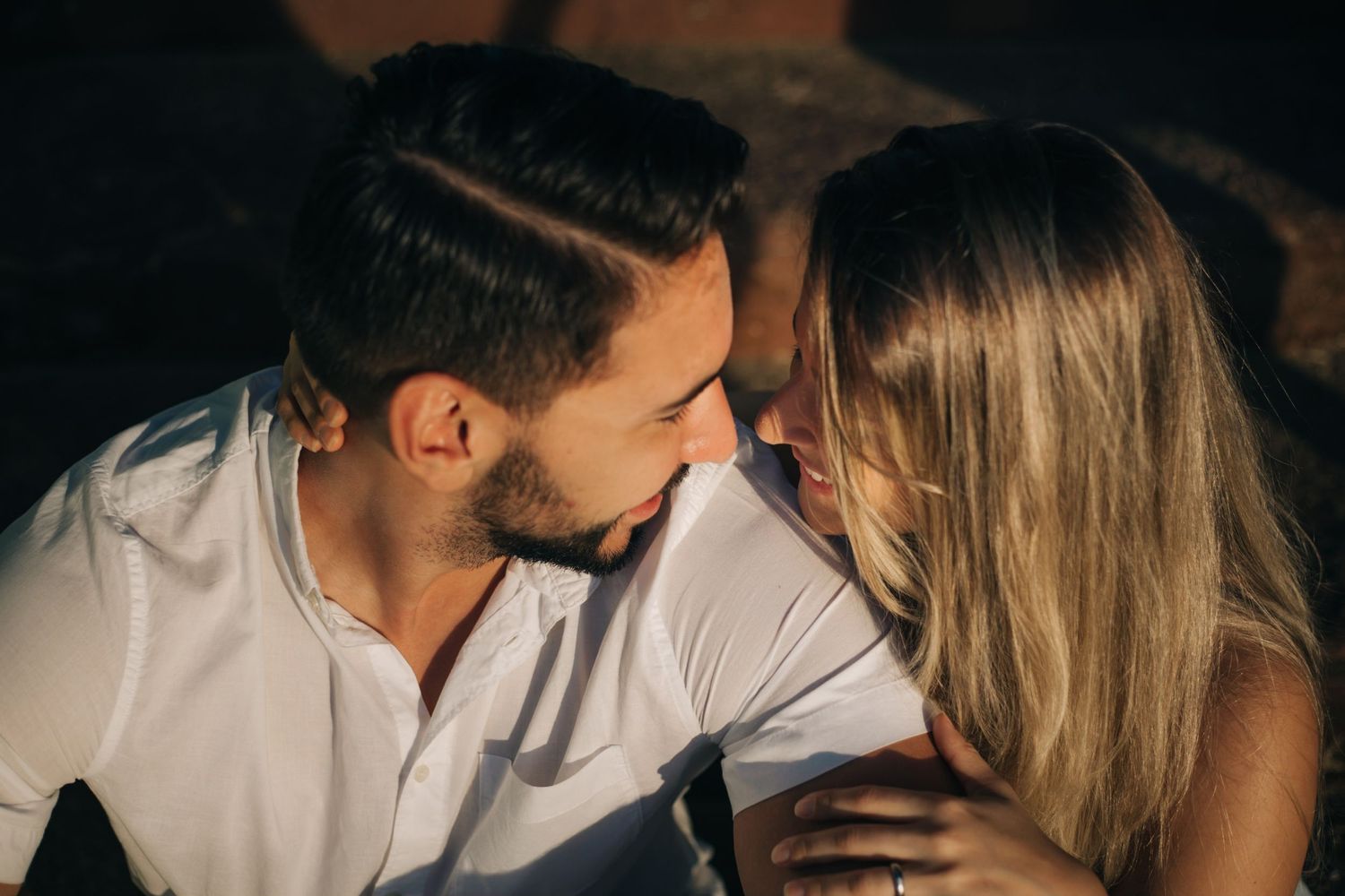 Atmospheric photo of couple in casual wear sharing tender moment on steps.