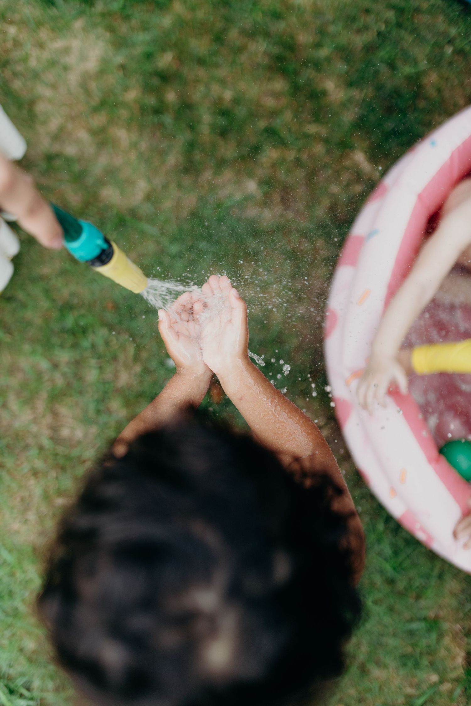 Blurred action shot of water splashing in a pink kiddie pool during playtime.