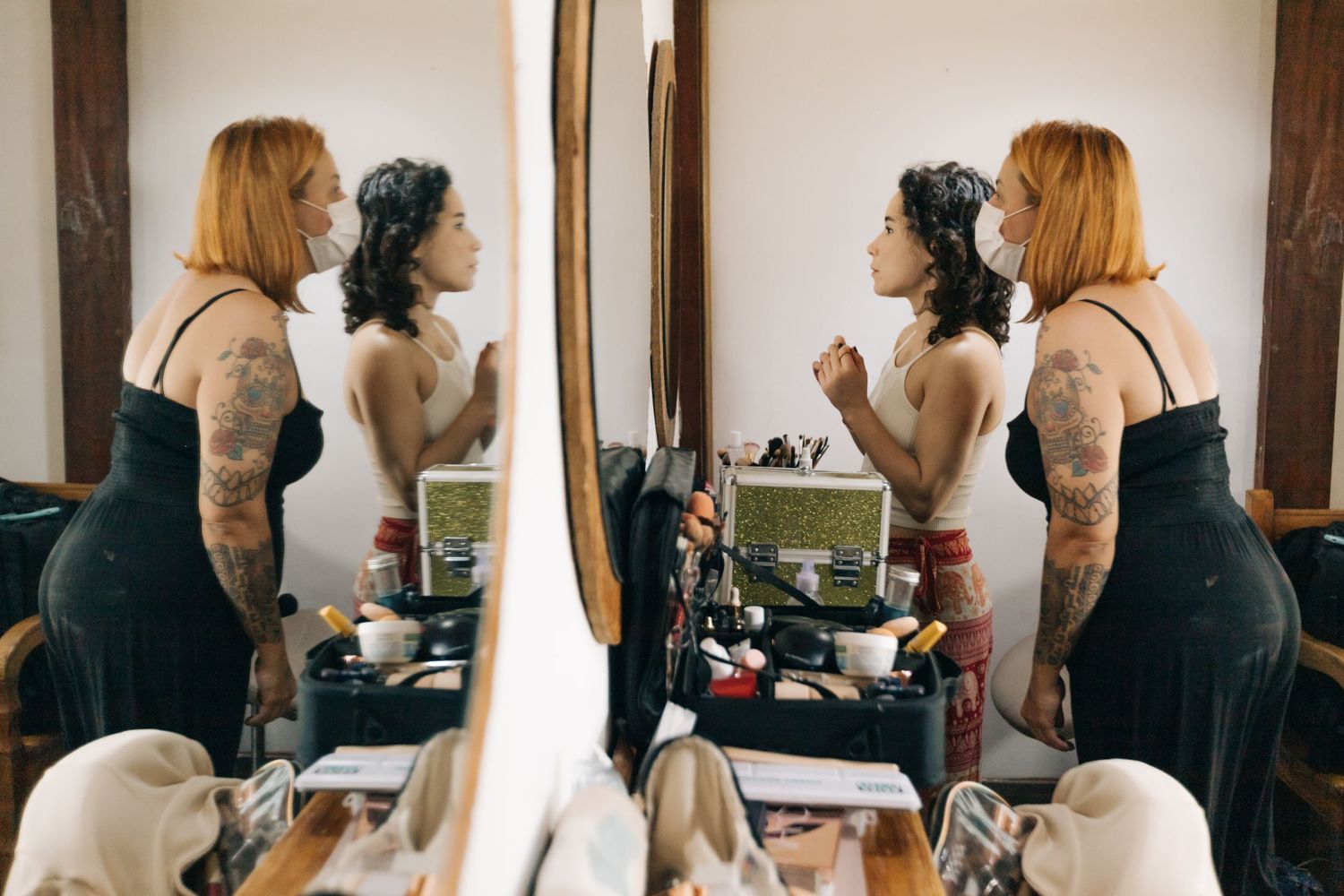 Several women getting ready in a bridal preparation room with mirrors and styling tools.
