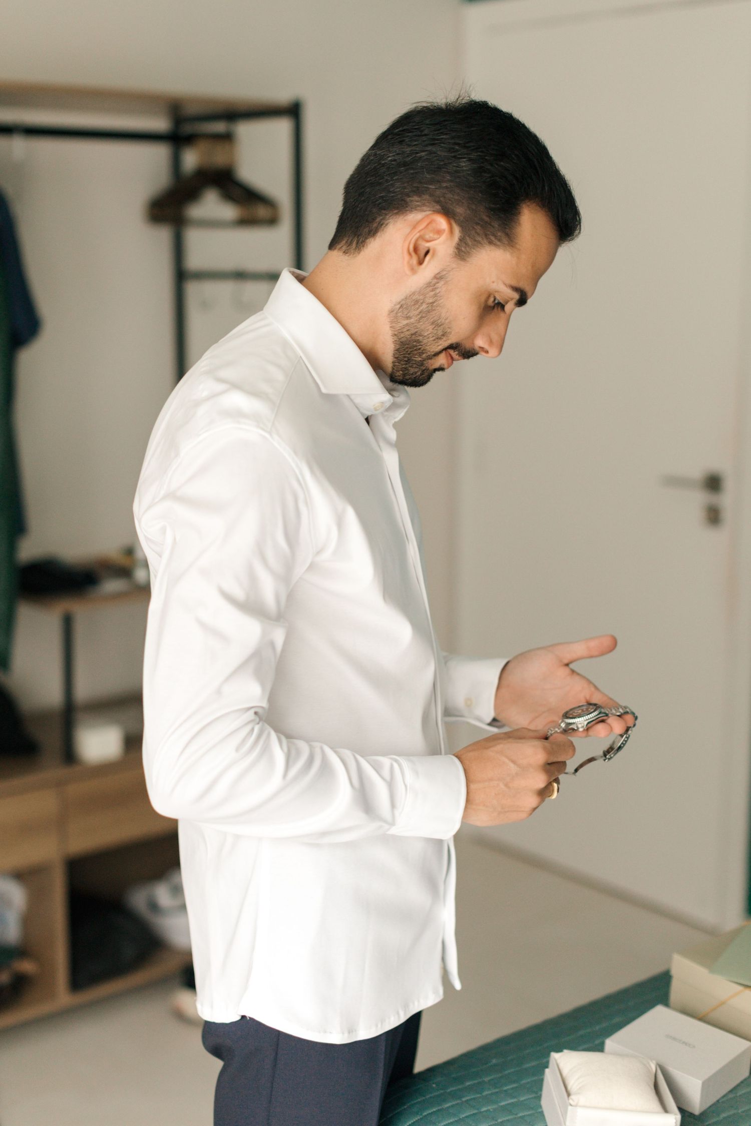 A person in a crisp white shirt checks their phone while getting ready in a dressing room.
